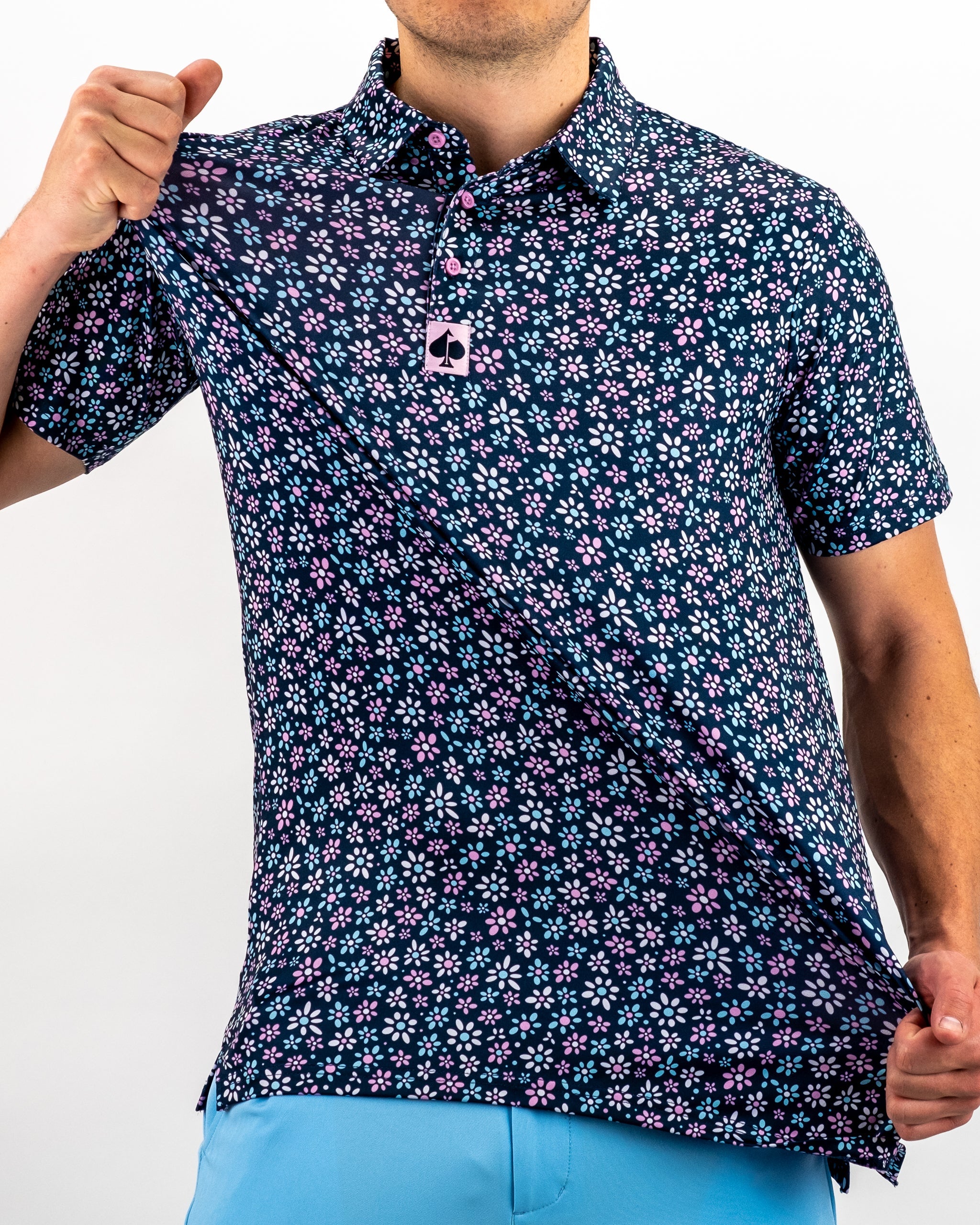 Men's short-sleeve golf shirt featuring a navy background with a vibrant pink and white daisy pattern, showcasing a playful style.