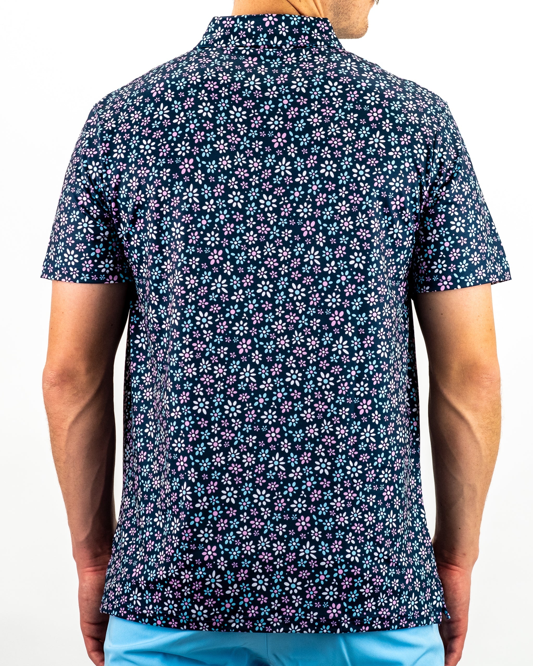 Men's short-sleeve golf shirt featuring a navy background with a vibrant daisy floral pattern in pink and white.