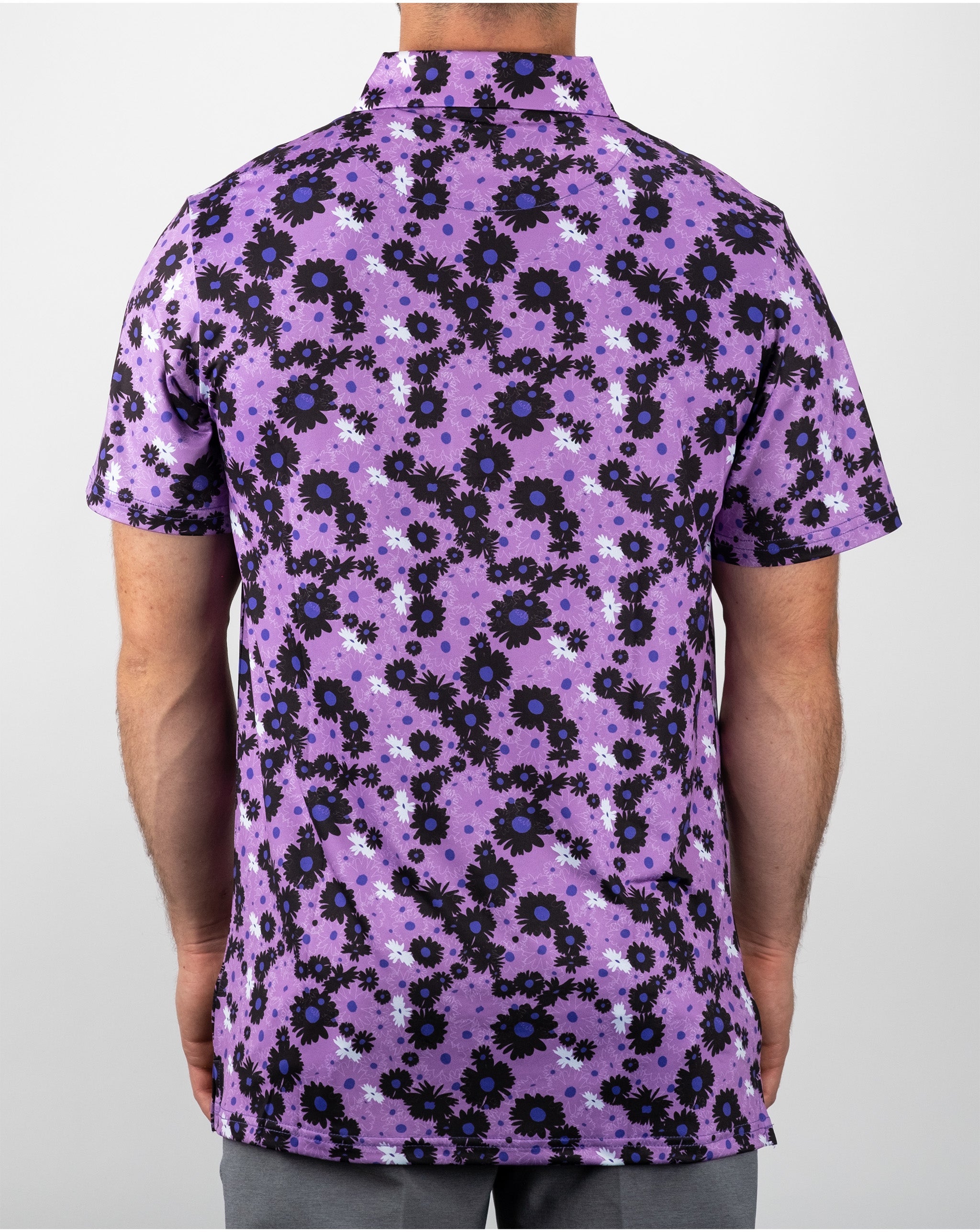 Men's short-sleeve golf shirt featuring a vibrant dark daisy floral pattern on a purple background.