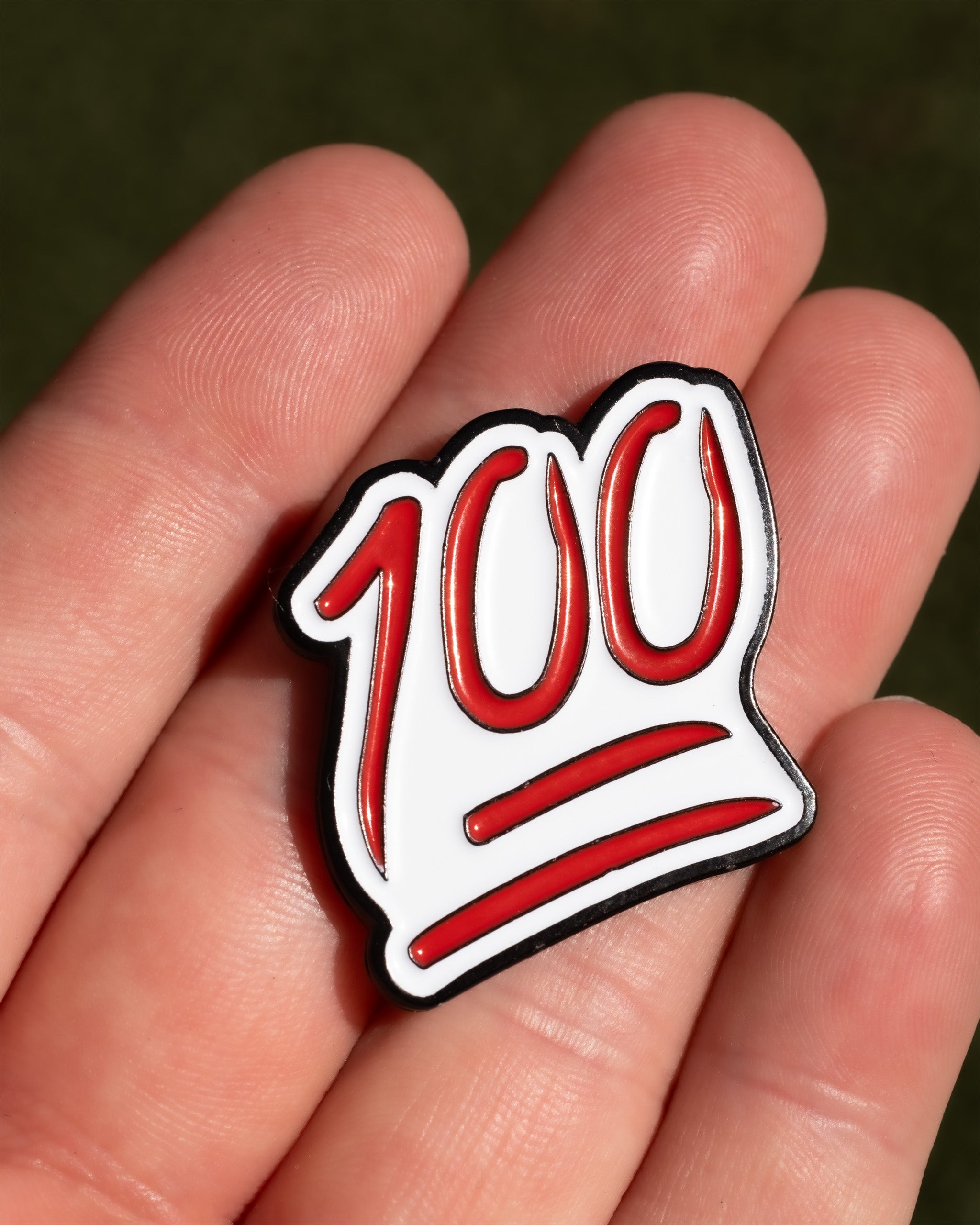 Bold 100 ball marker held in a hand, featuring a red and white design for golfers who want to stand out on the course.