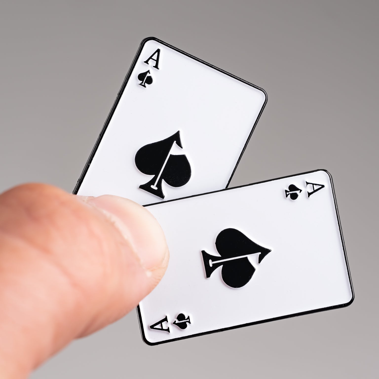 Ace of Spades ball marker held between fingers, featuring a classic playing card design with bold black spade symbols.