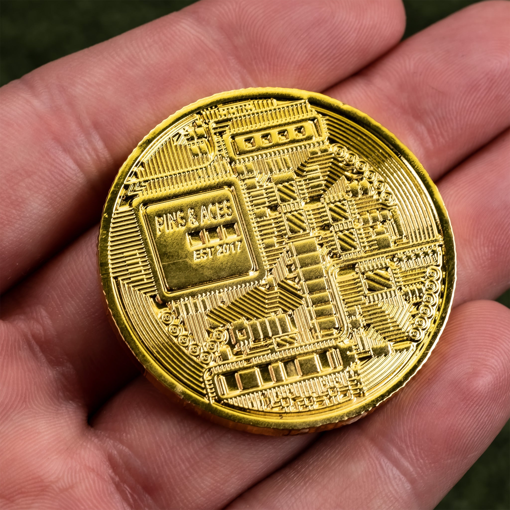 Gold Bitcoin ball marker with intricate circuit design, held in a hand, showcasing unique golf accessory for enthusiasts.