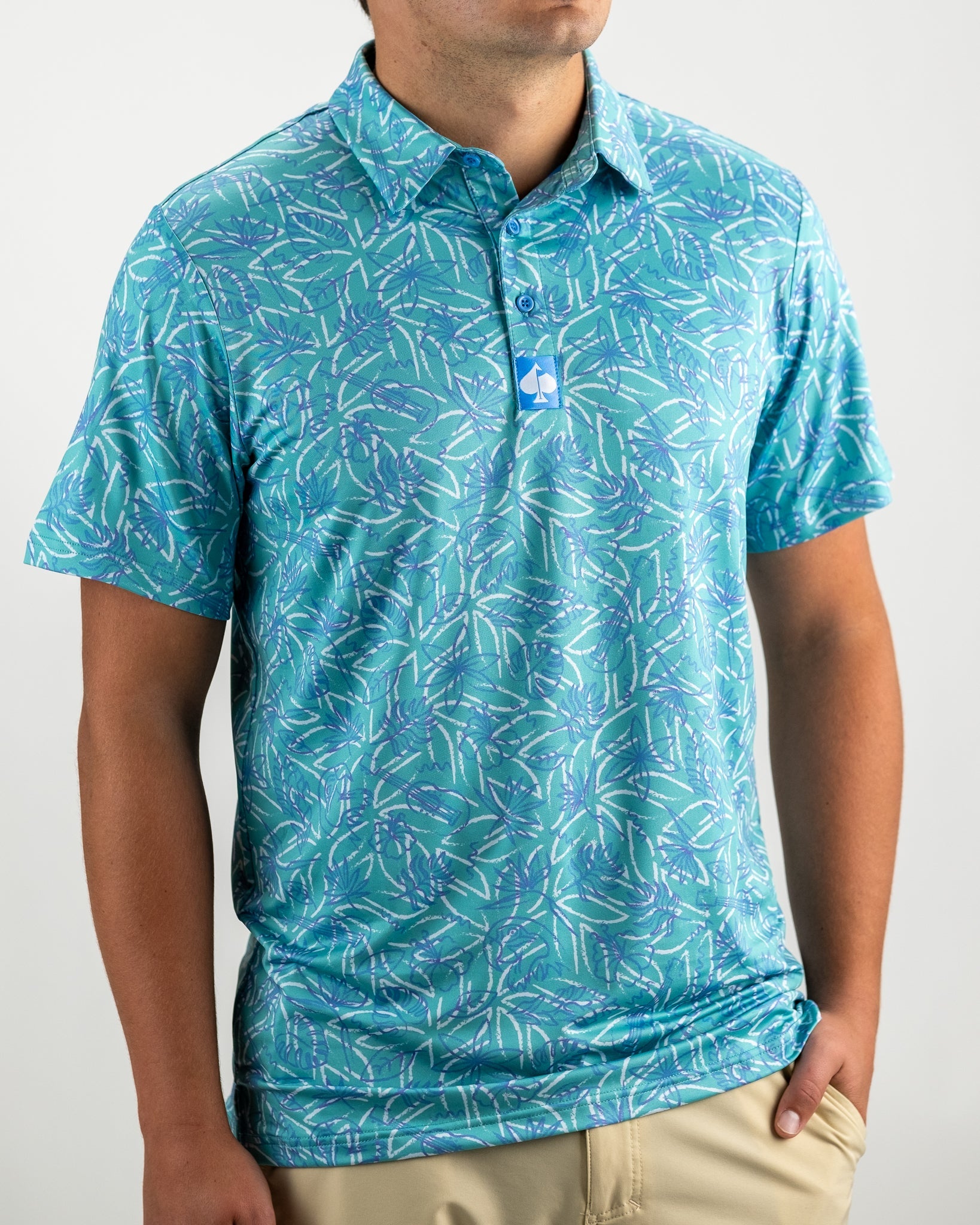 Men's Margaritaville 5 O'Clock Ocean polo shirt featuring a vibrant tropical leaf pattern in shades of blue and green.