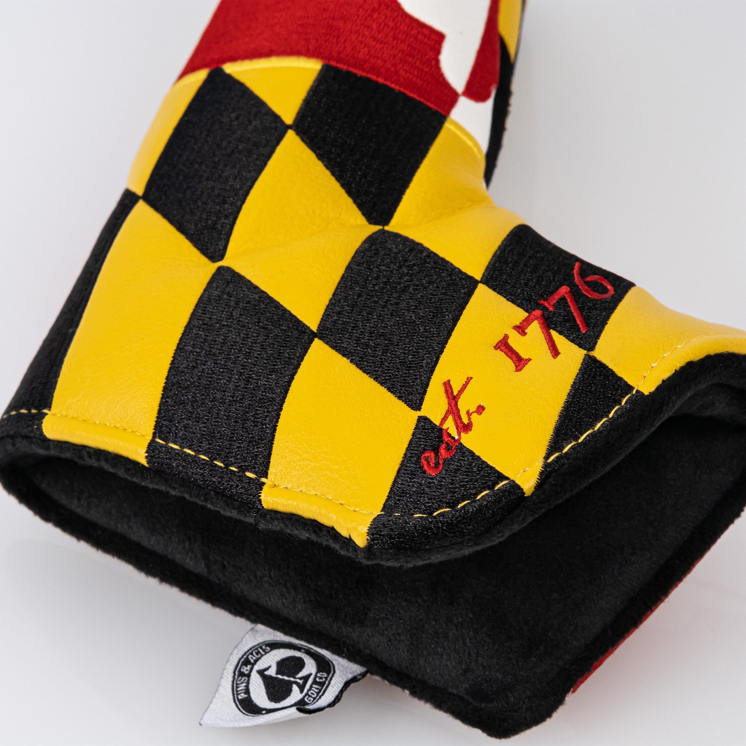 Bold Maryland blade putter cover featuring a vibrant checkerboard design in red, yellow, and black with established 1776 detail.