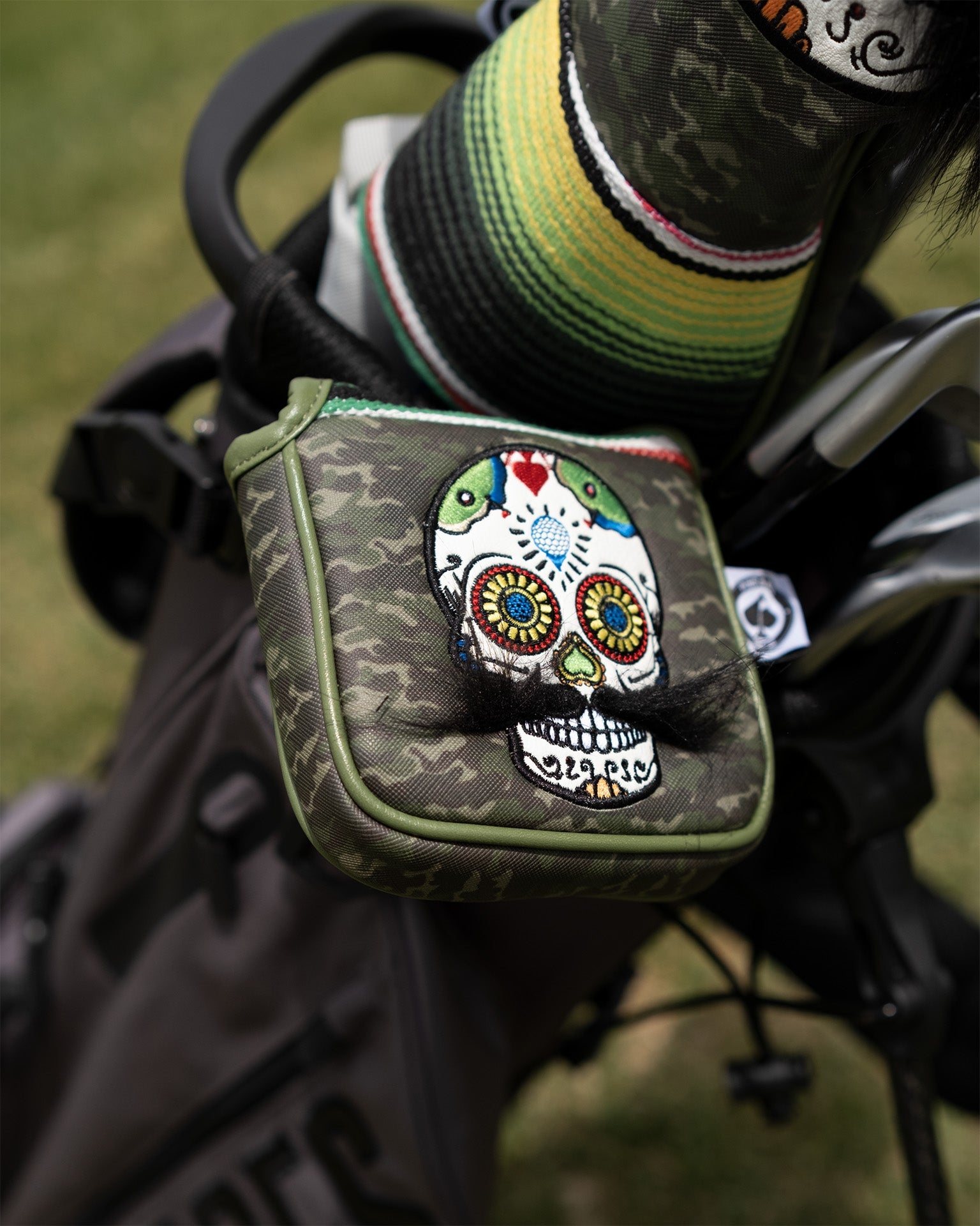 Green camo mallet putter cover featuring a colorful mustache sugar skull design, perfect for stylish golfers.
