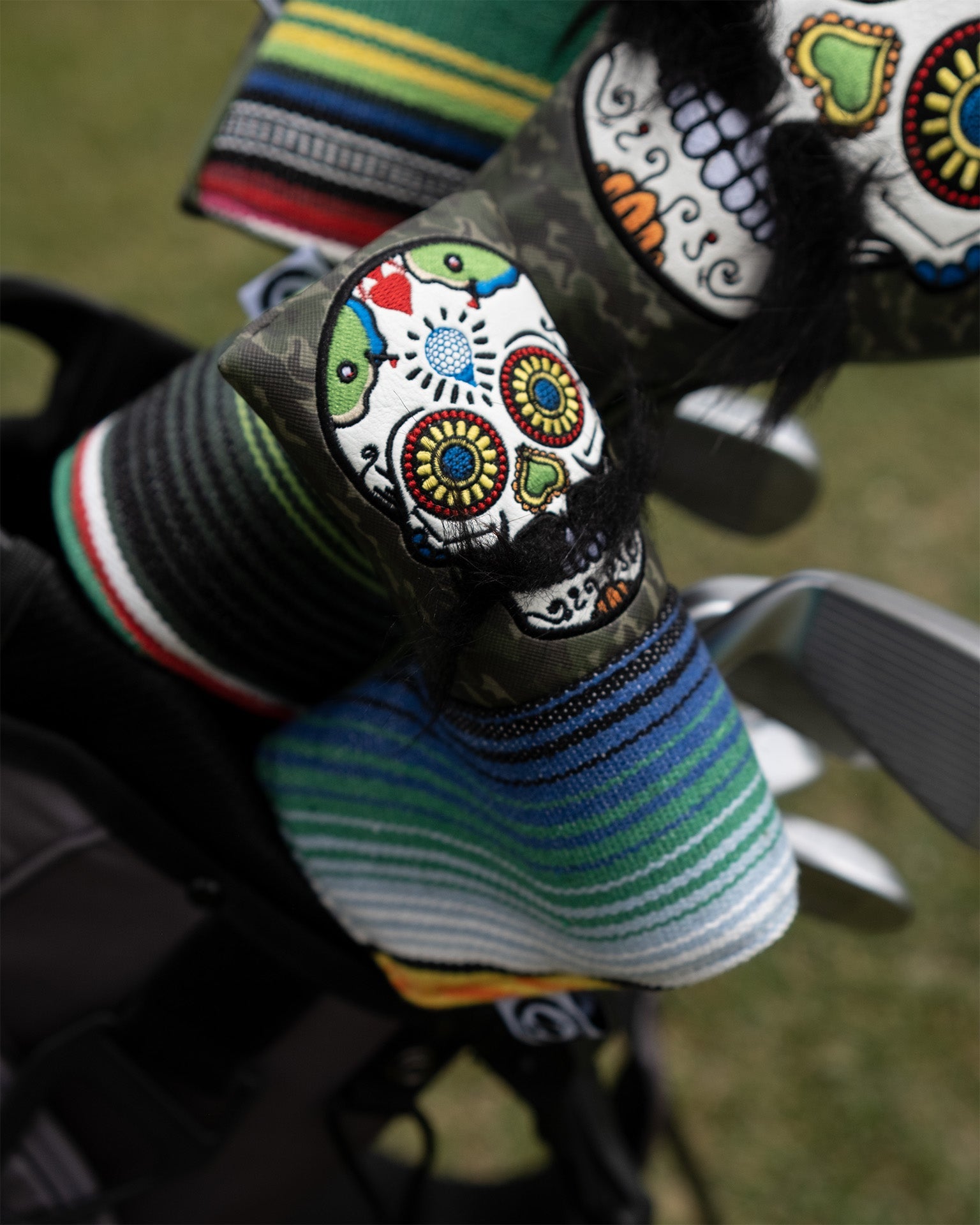 Alt text: Green camo putter cover featuring a mustache sugar skull design.