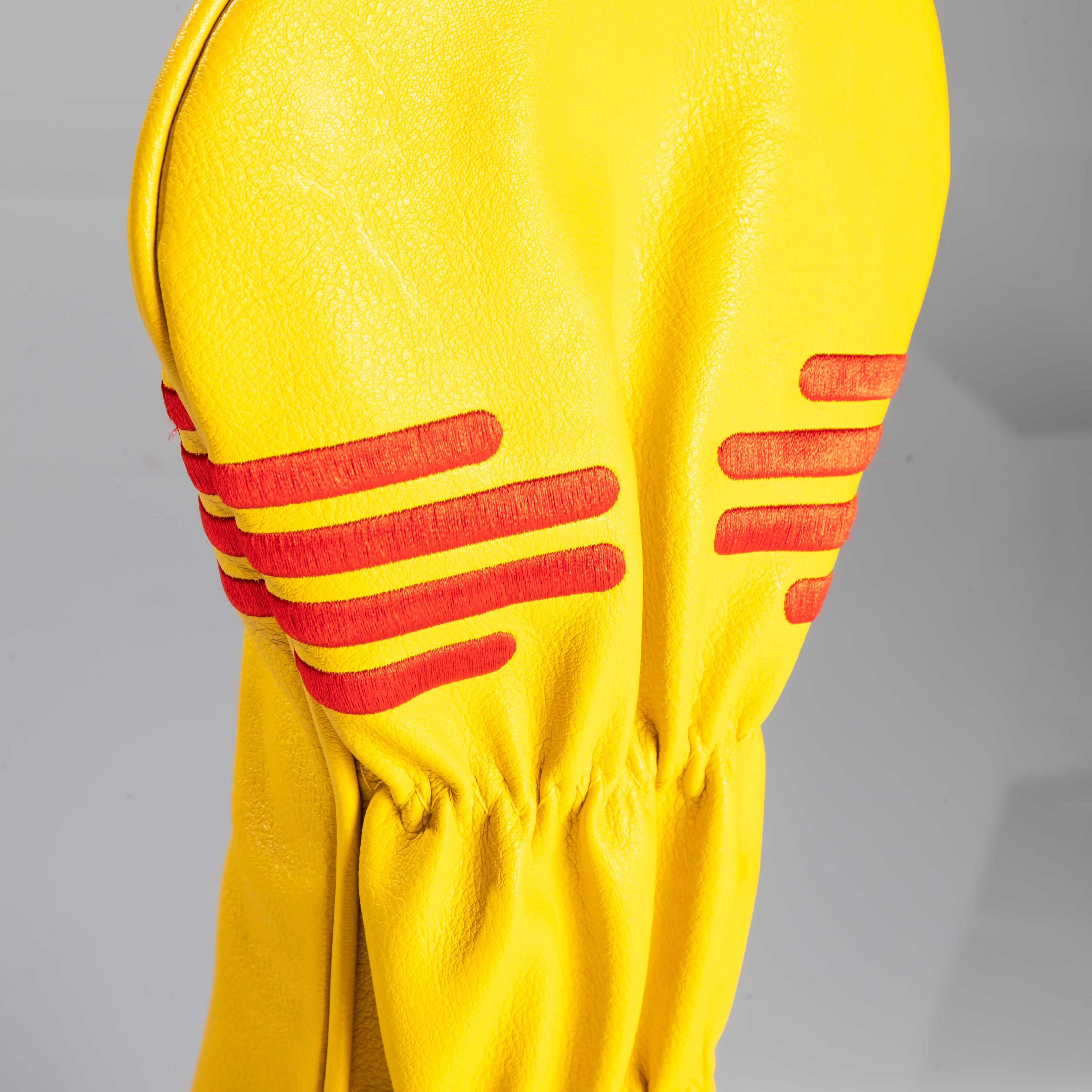 New Mexico State Flag driver cover featuring a vibrant yellow design with red Zia sun symbol accents.