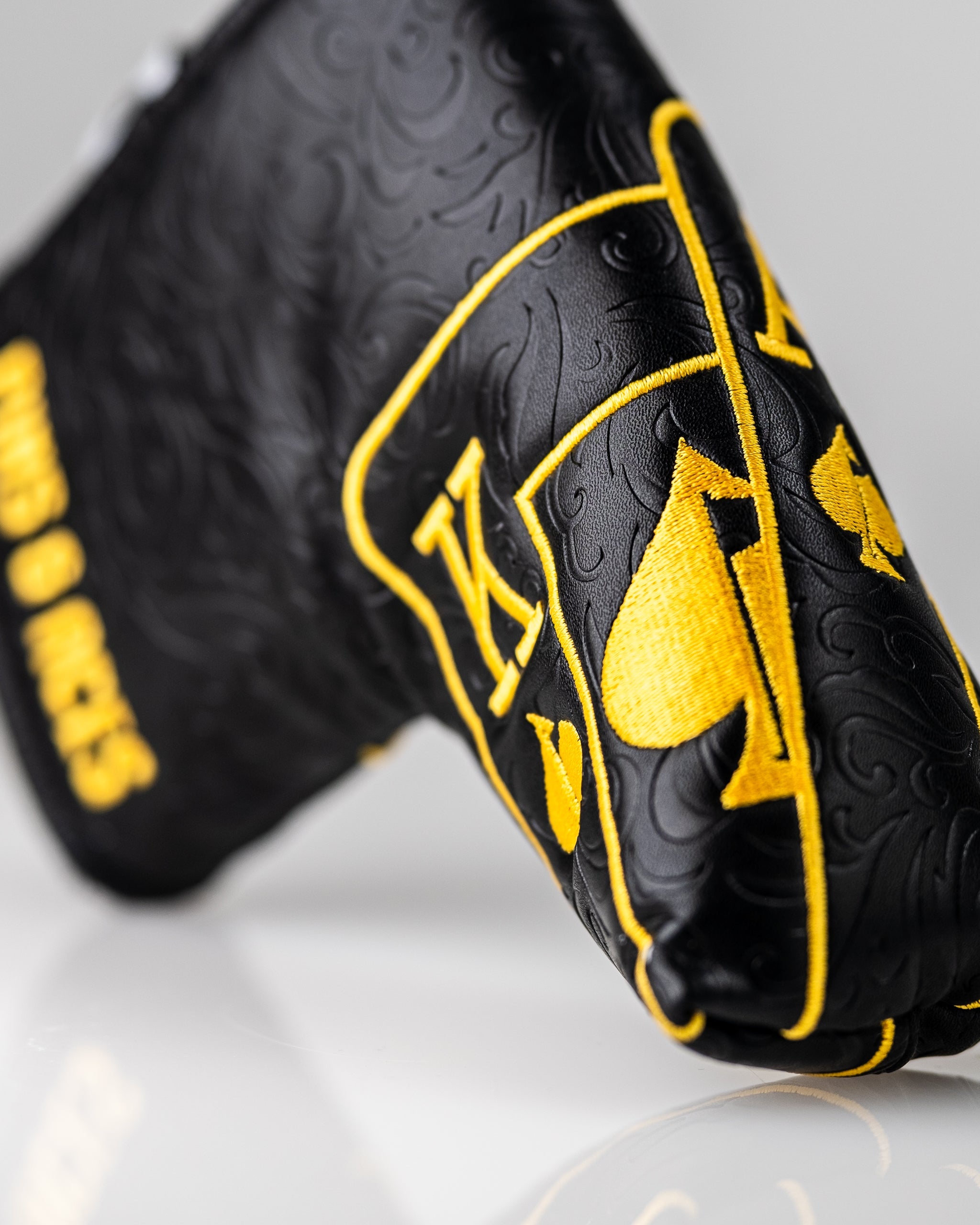 Black and gold Ace of Spades blade putter cover featuring intricate designs and bold branding for stylish golfers.
