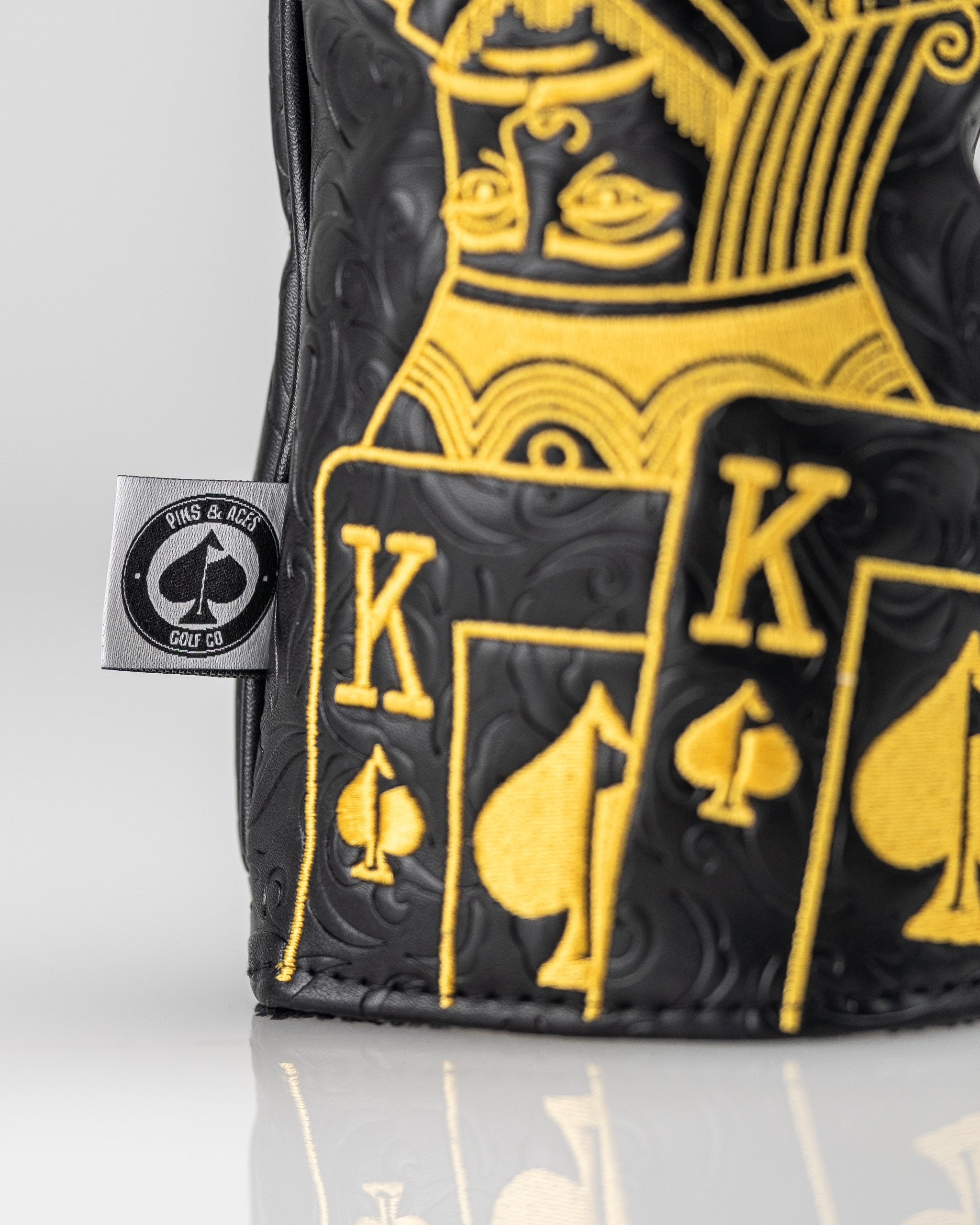 Black and gold driver cover featuring a King of Spades design with intricate detailing and a logo tag.