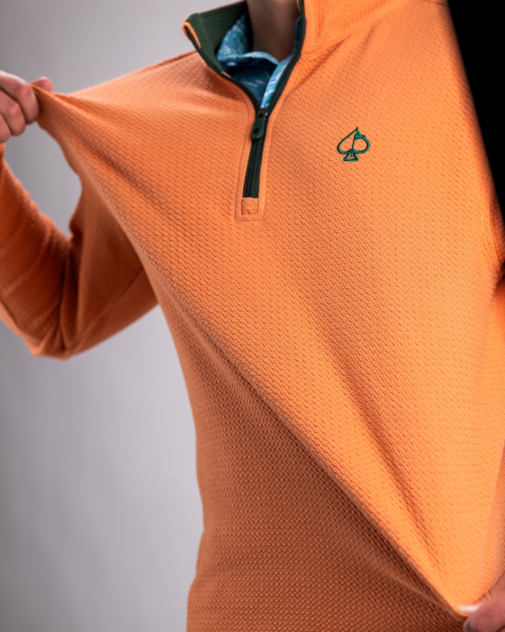 Player Preferred Waffle Knit Pullover in pumpkin orange, featuring a quarter zip and a green collar, ideal for stylish golfers.