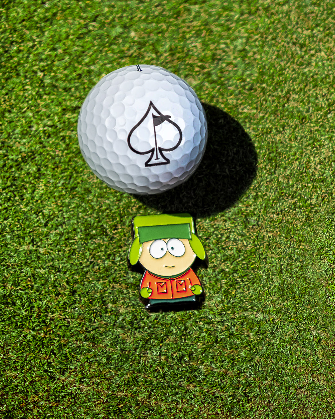 South Park Kyle ball marker positioned next to a golf ball on a green, showcasing a playful golf accessory for fans.
