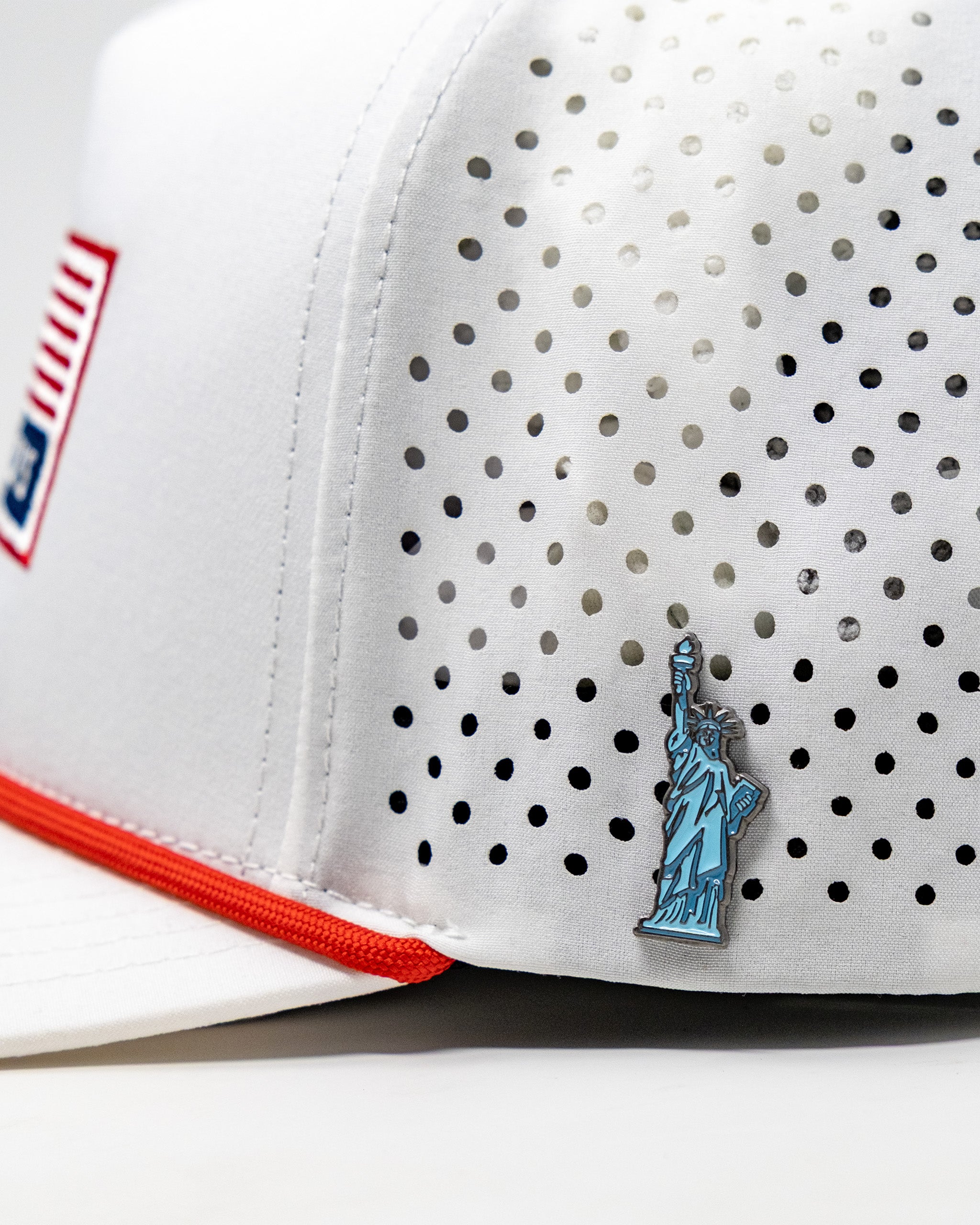 Perforated white rope hat with a small Statue of Liberty pin, featuring a red and blue USA logo patch on the side.