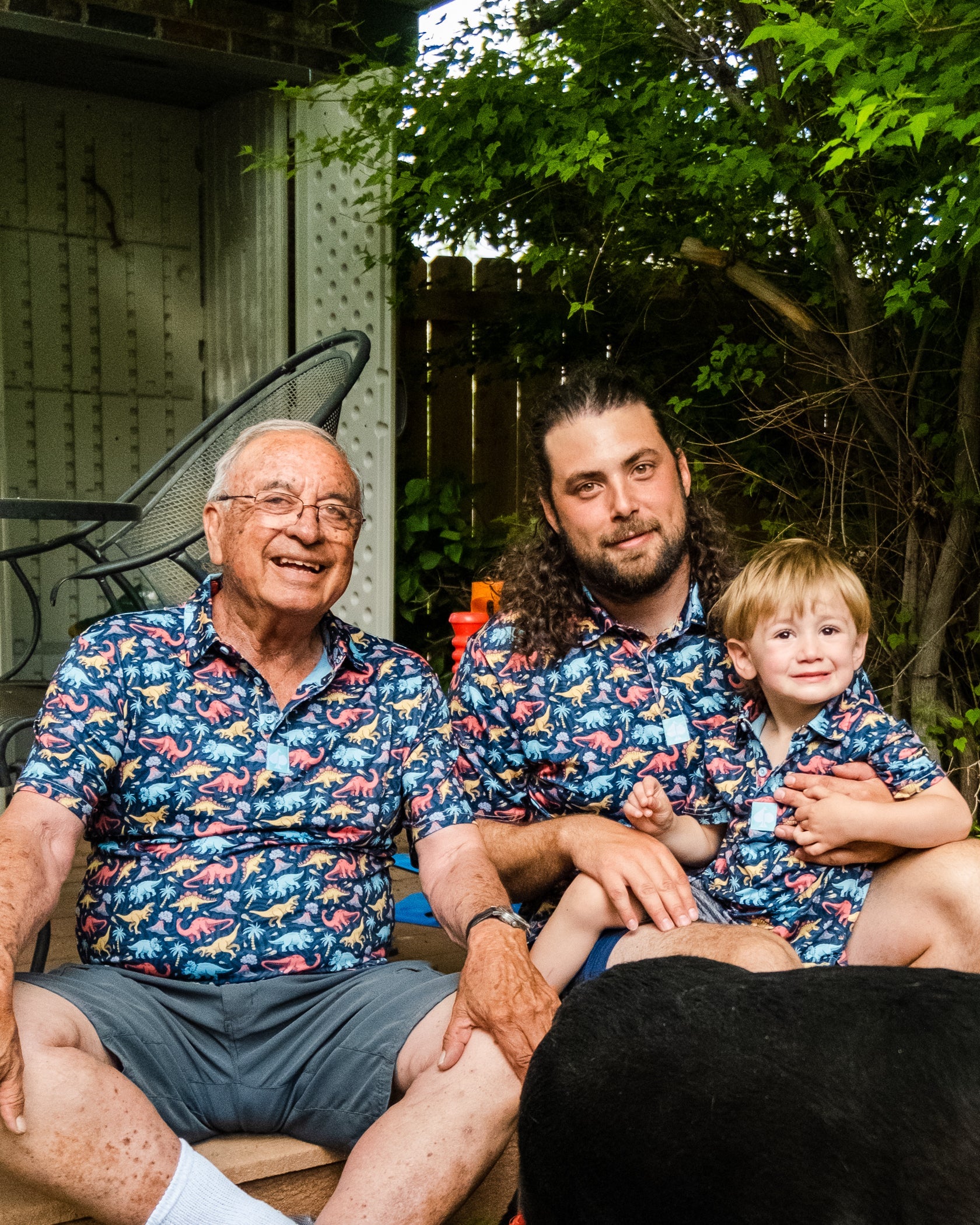 Youth Jurassic Polo featuring a vibrant dinosaur print, worn by a young boy with family members in matching shirts.
