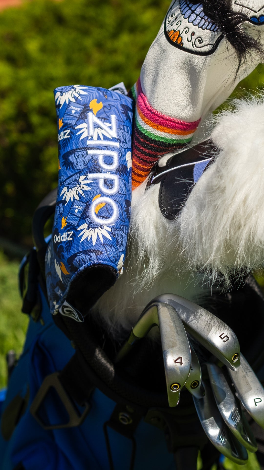 Bold Zippo blade putter cover in blue floral design, displayed on a golf bag alongside colorful headcovers and clubs.