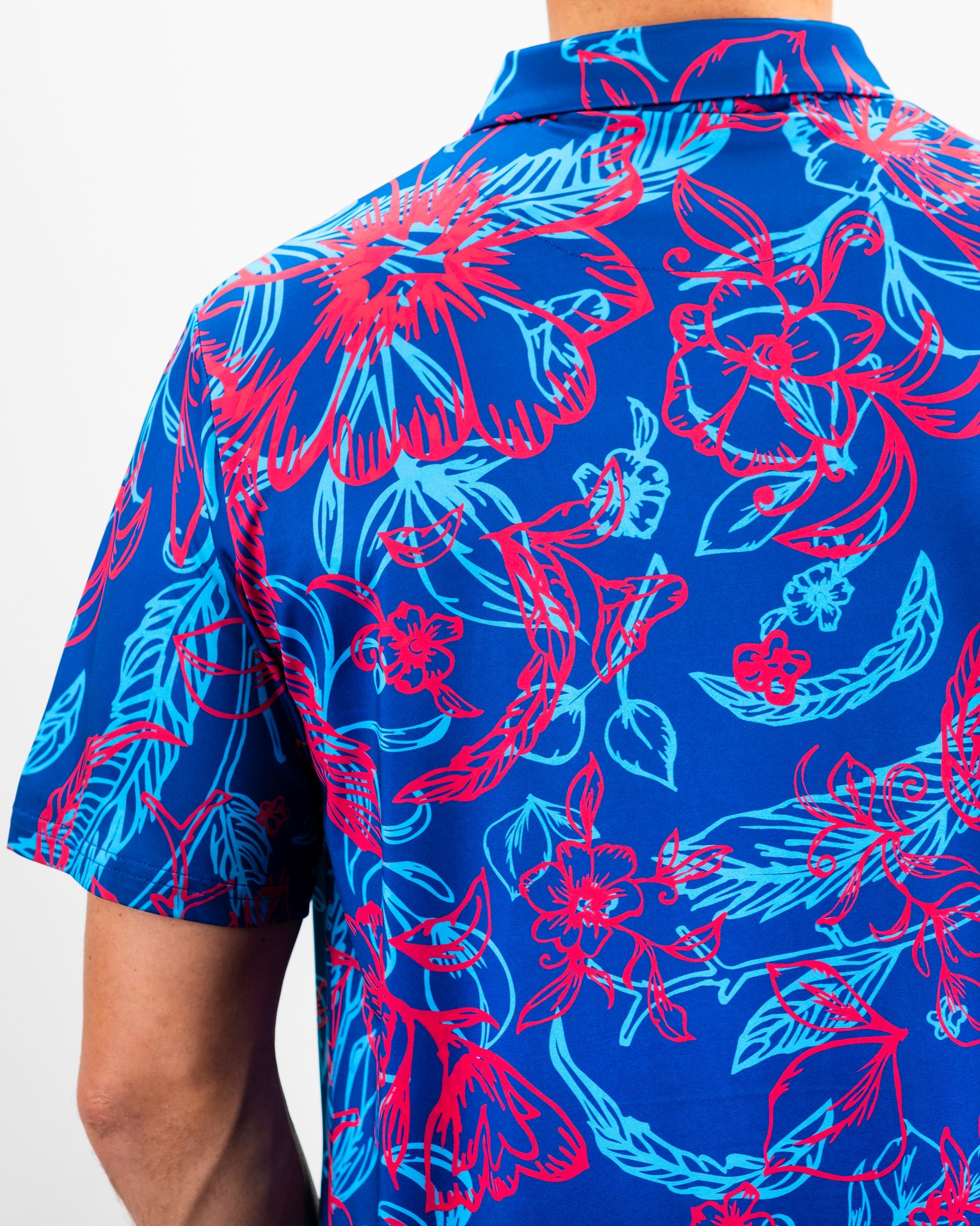 Bold blue golf shirt featuring vibrant red and turquoise floral patterns, perfect for making a statement on the course.