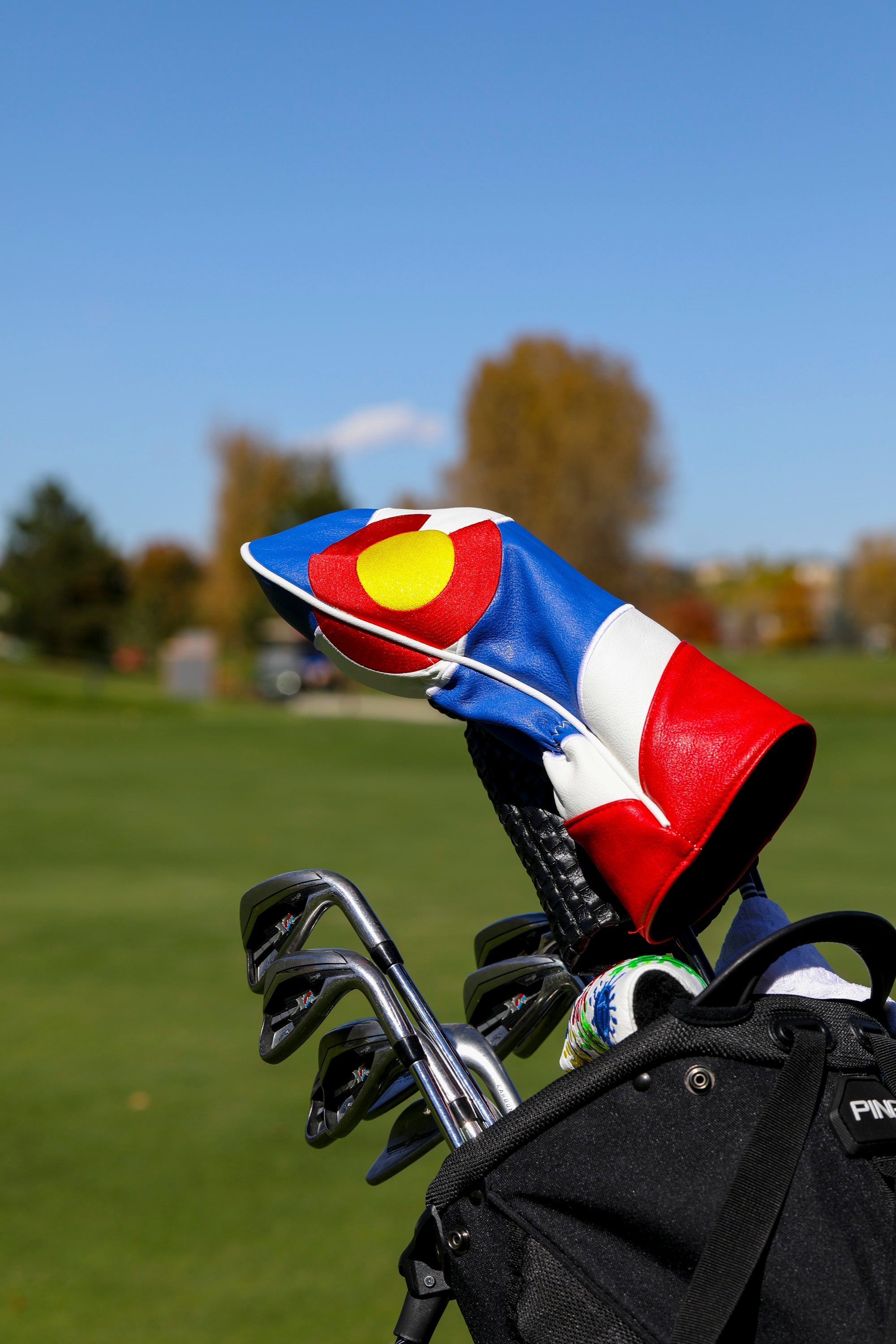 Colorado State Flag driver cover displayed on a golf bag, showcasing vibrant colors against a clear blue sky.