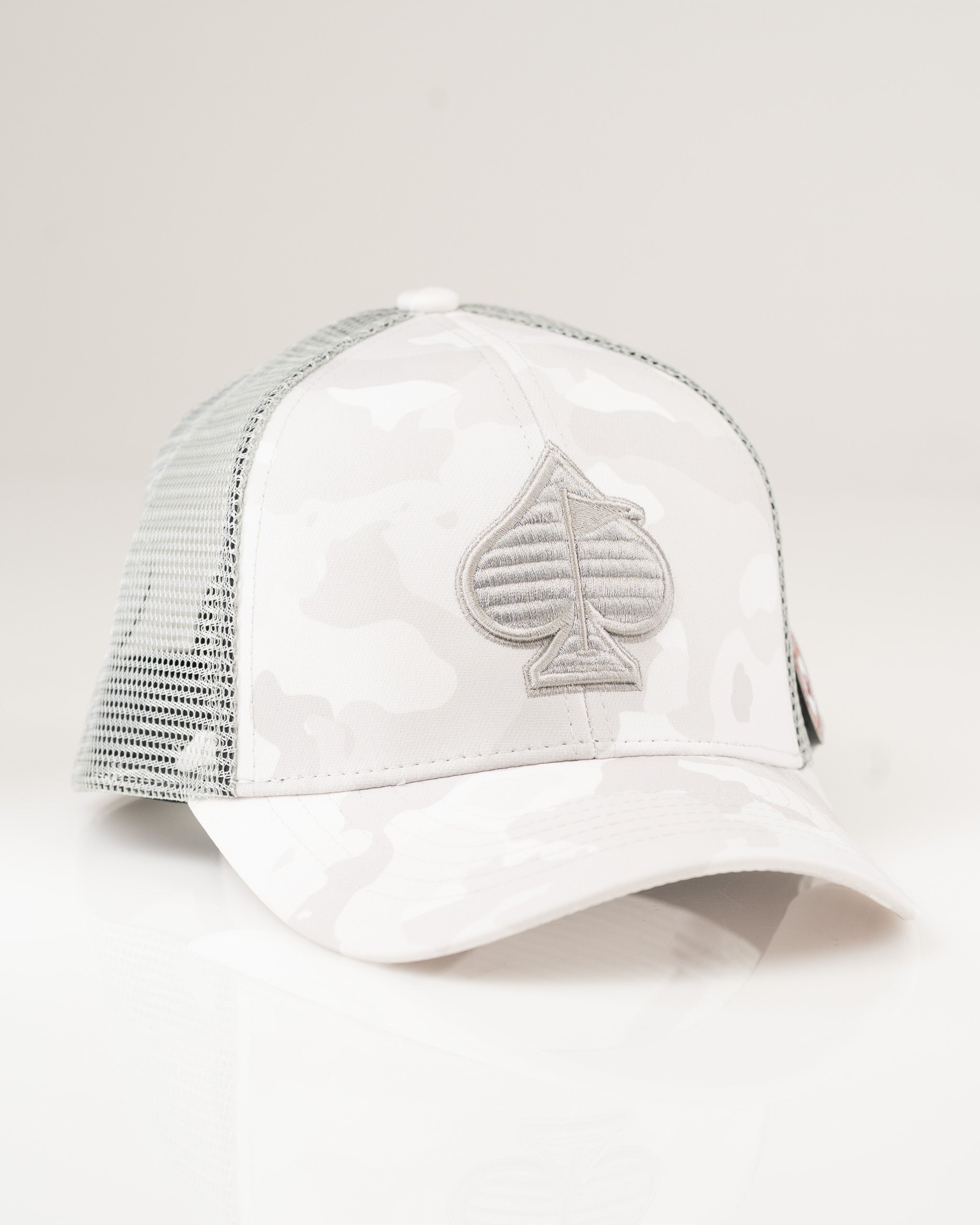 Trucker hat in Arctic Camo featuring a gray spade logo on a white and gray camouflaged design. Ideal for stylish golfers.