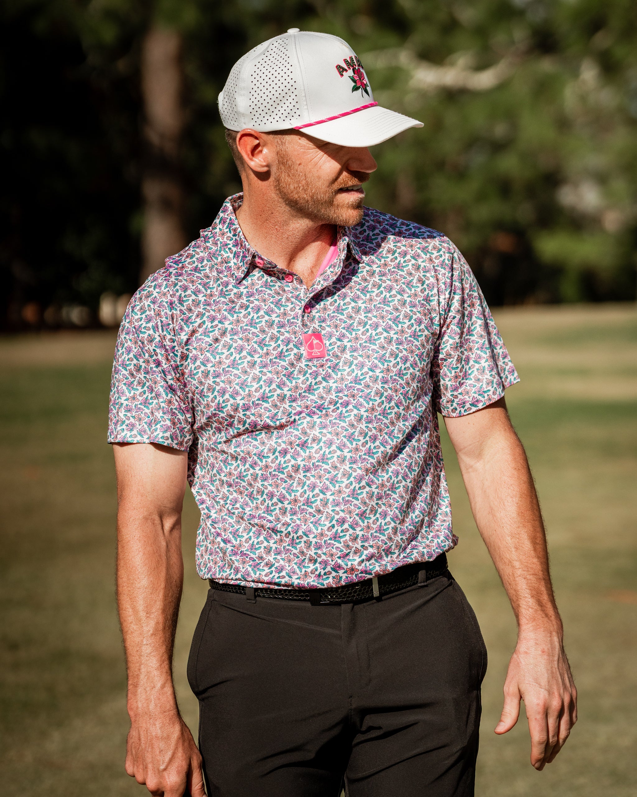 Men's light azalea golf shirt featuring a vibrant floral pattern, paired with a stylish cap, perfect for standout performance on the course.