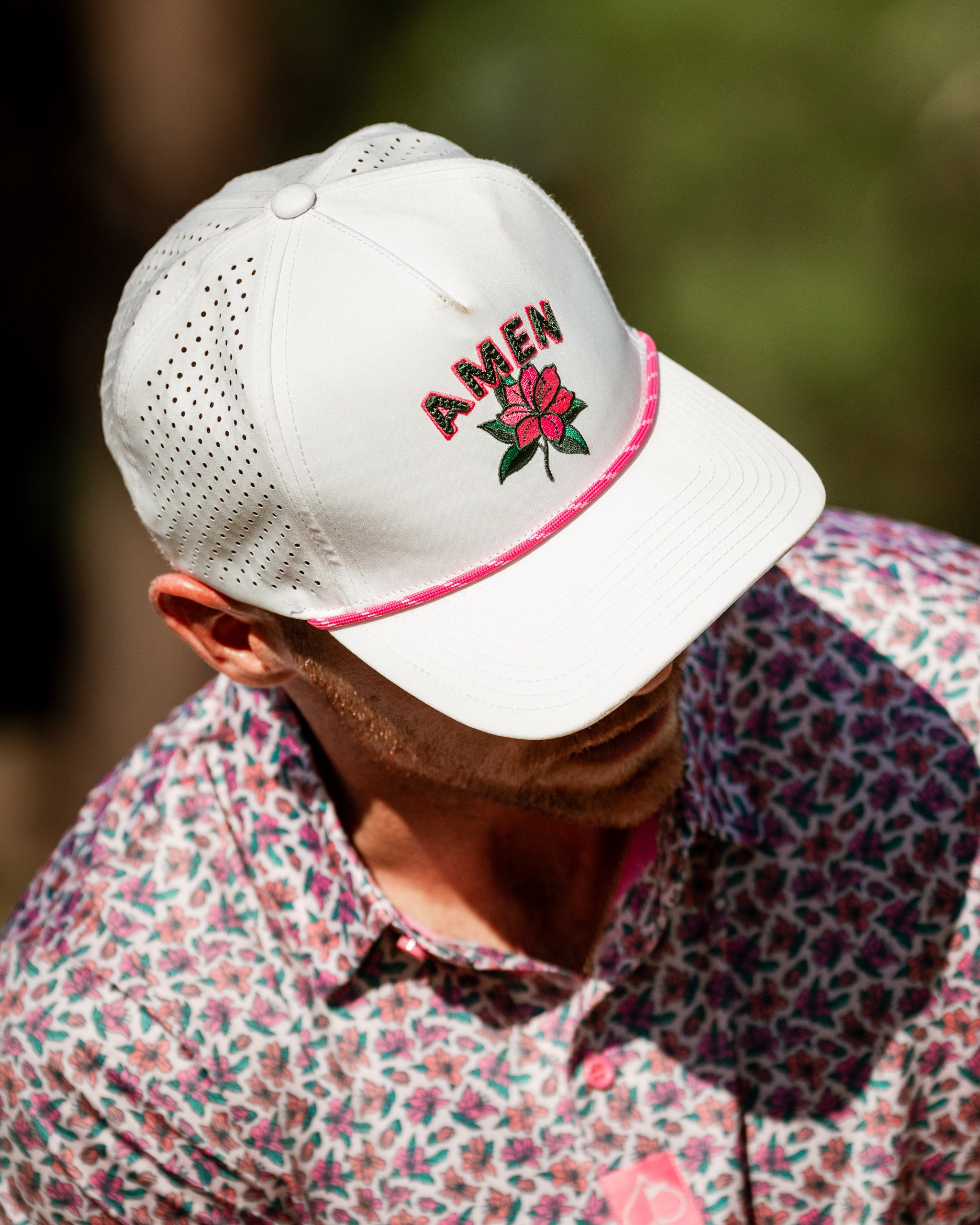 Light Azalea golf cap featuring a floral design and "AMEN" embroidery, paired with a vibrant patterned shirt.
