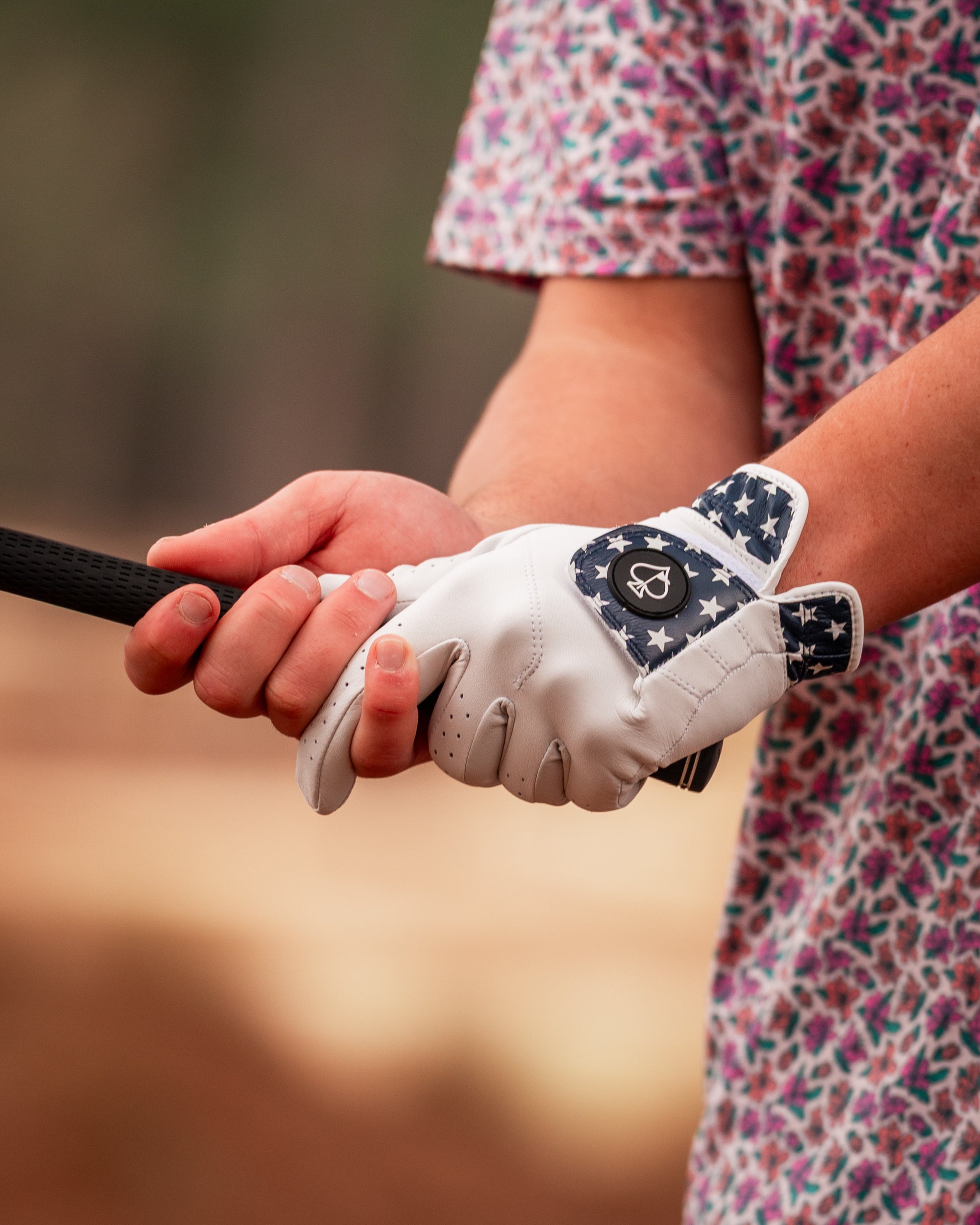 Light Azalea golf glove featuring a patriotic star design, held by a golfer gripping a club on the course.