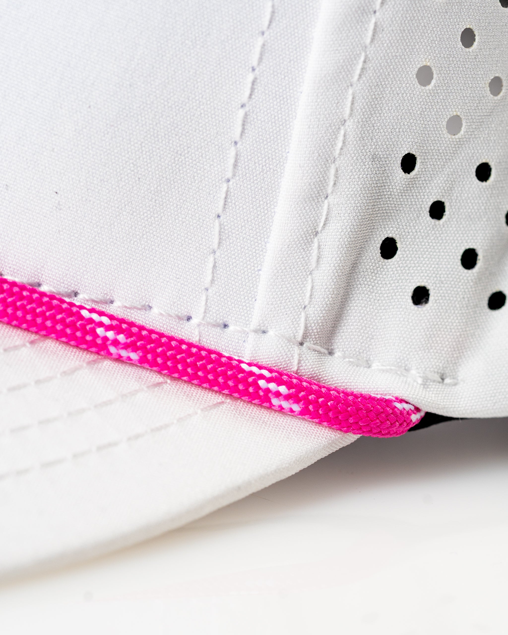 White perforated rope hat featuring a vibrant pink rope accent, ideal for stylish golfers seeking standout accessories.
