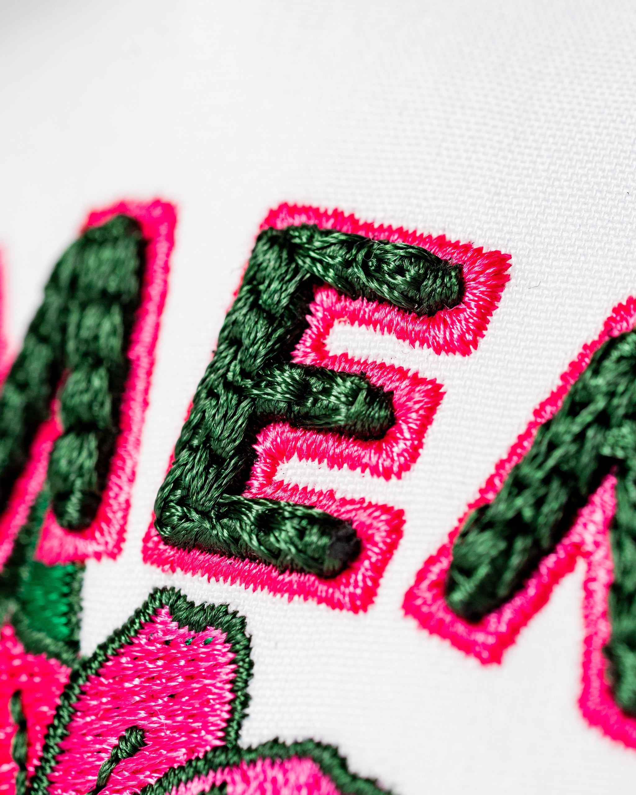 Perforated white rope hat featuring vibrant pink and green embroidered "AMEN" and floral design for stylish golf wear.