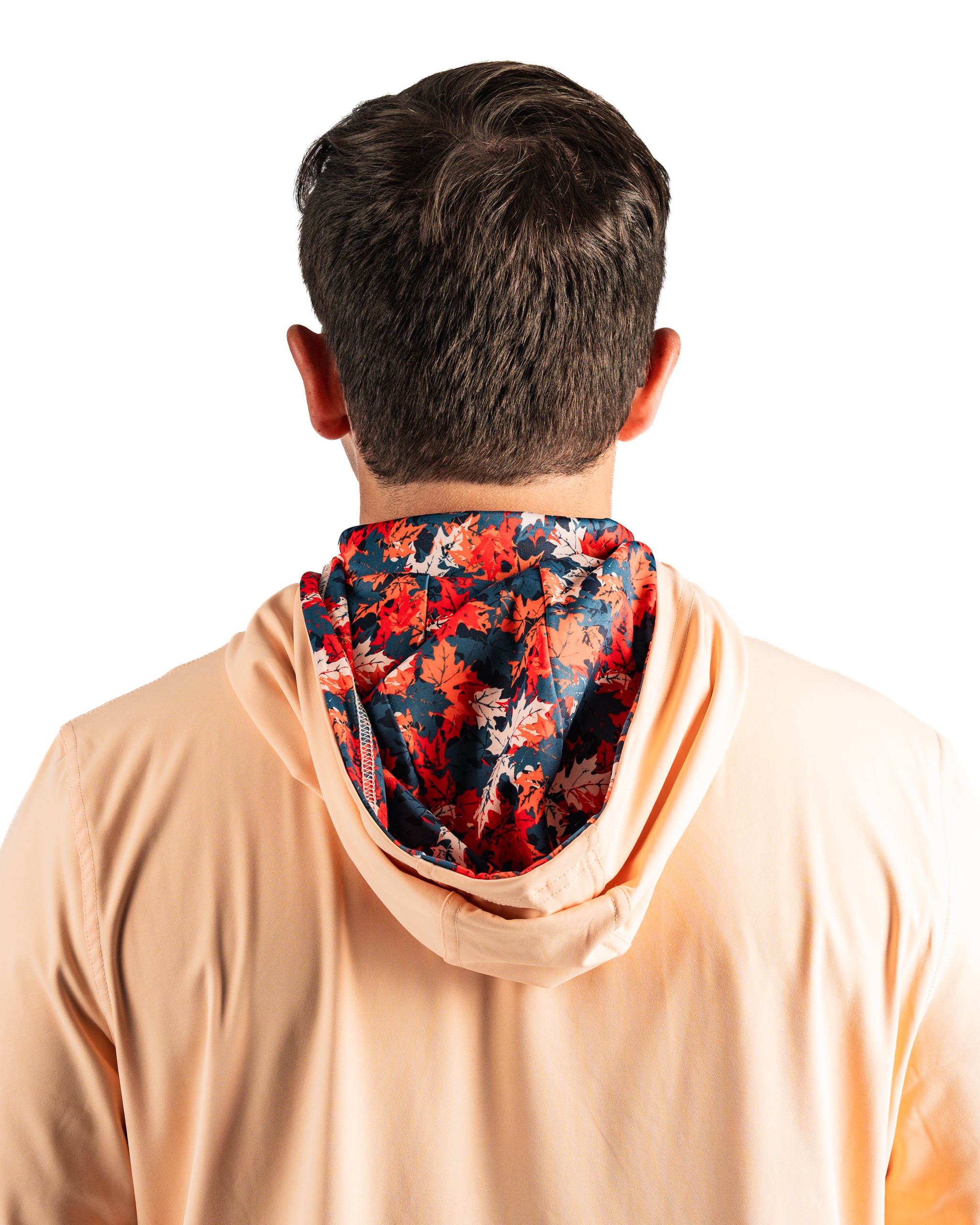 Men's performance golf hoodie in soft peach with a vibrant autumn leaves patterned hood, designed for comfort on the course.