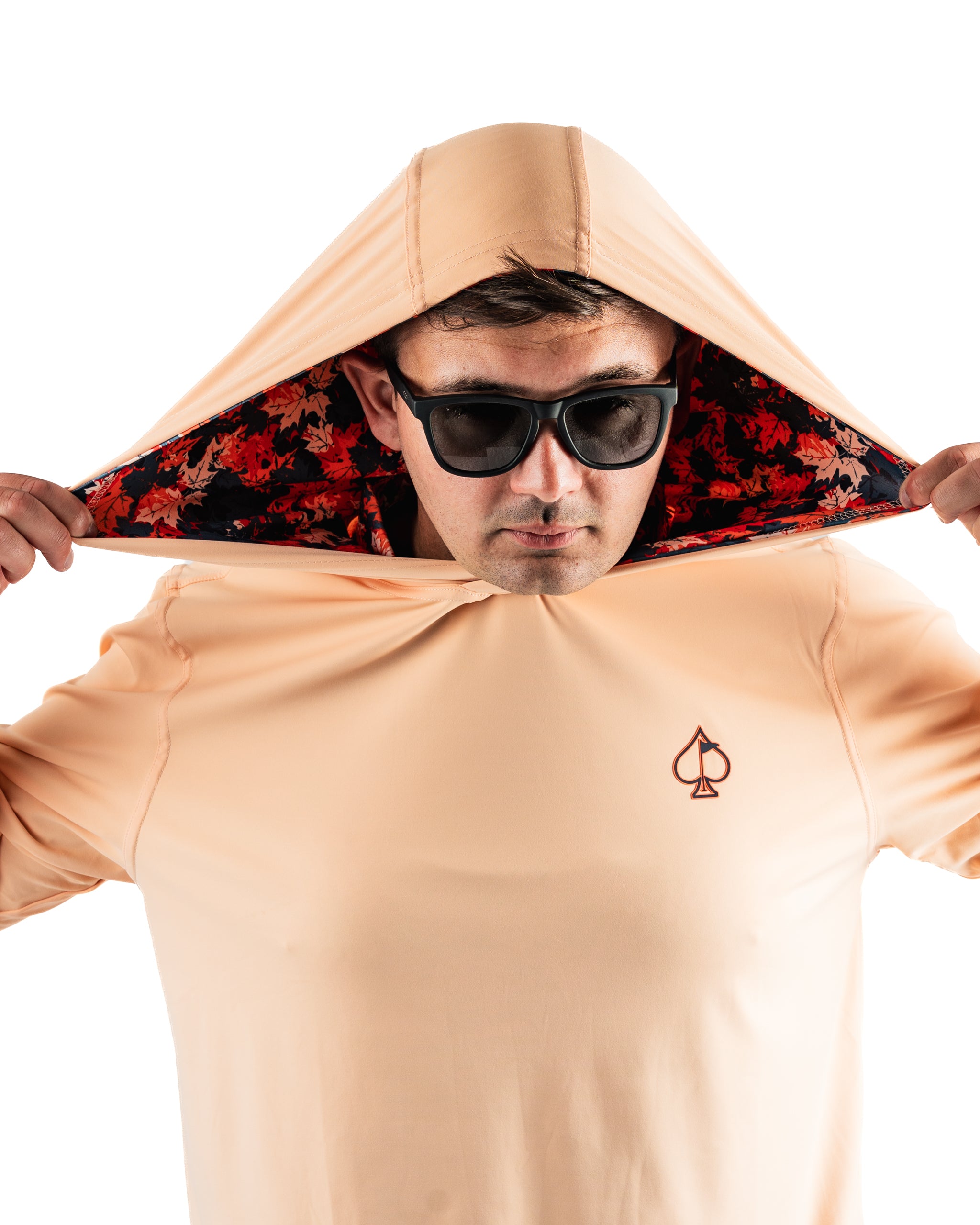 Man wearing a peach-colored performance golf hoodie with a floral-lined hood, showcasing a stylish and sporty look.