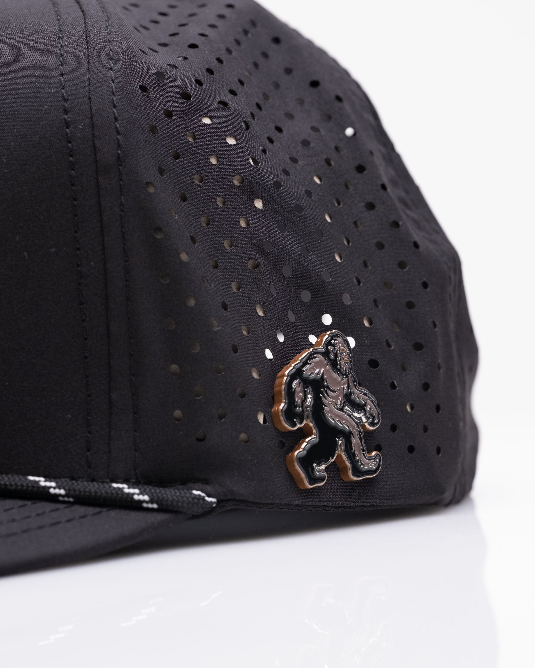 Black golf cap from the Sasquatch Collection featuring a perforated design and a Sasquatch emblem on the side.