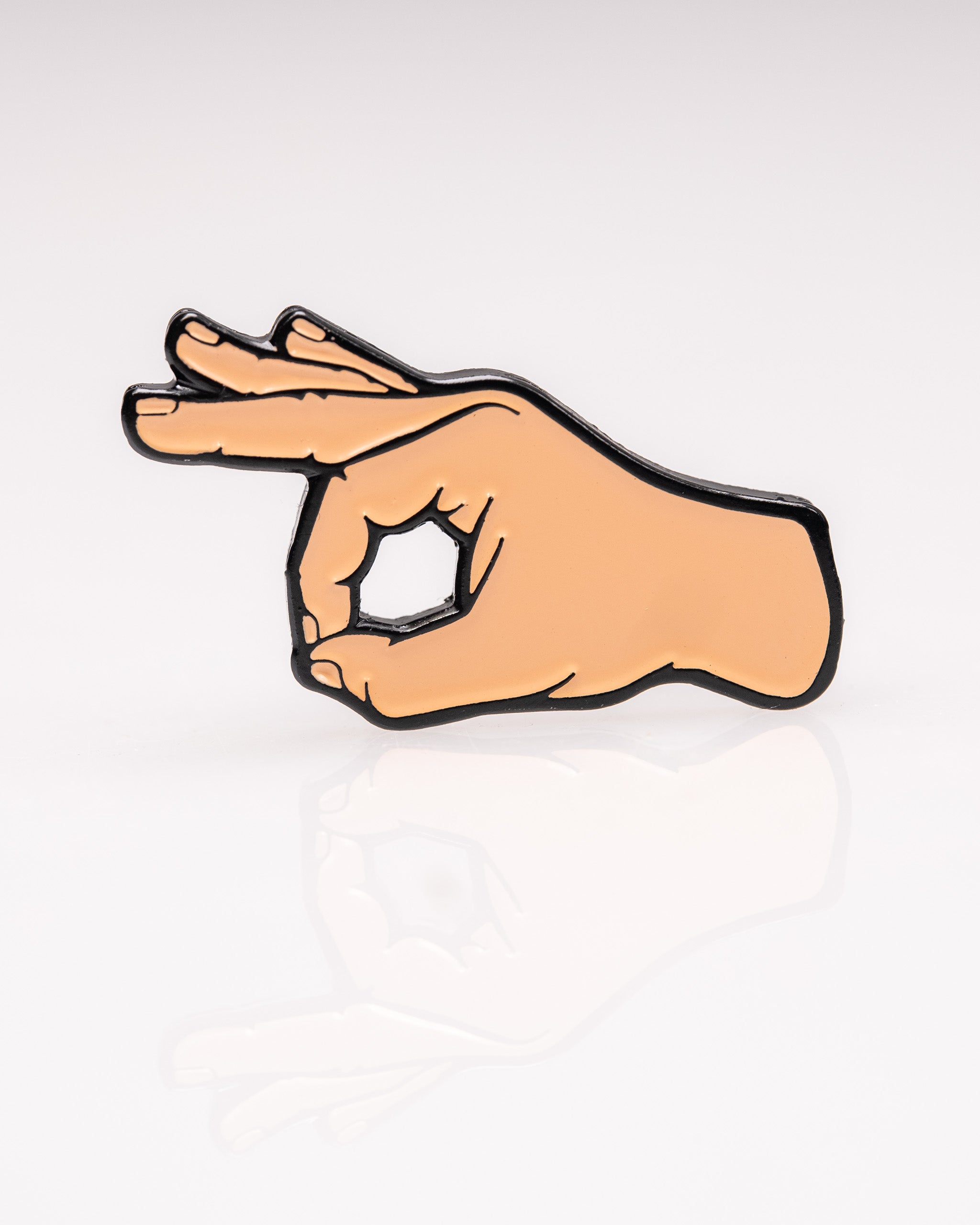 A hand-shaped enamel pin with an "OK" gesture, featuring a beige skin tone and black outline on a white background.