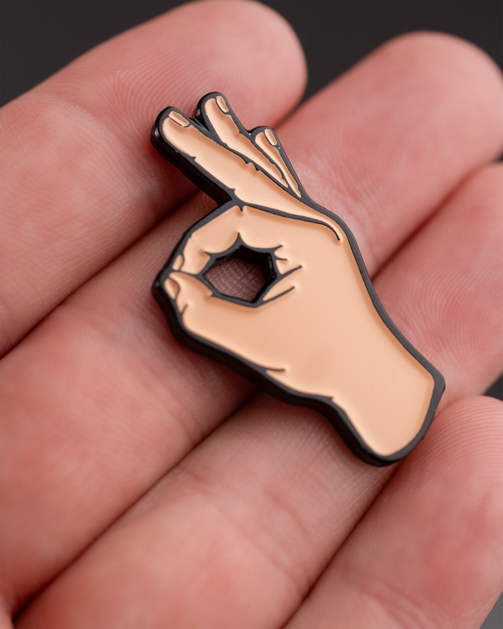 A hand holding a black-edged OK Hand Ball Marker shaped like a hand making an "OK" gesture with fingers.