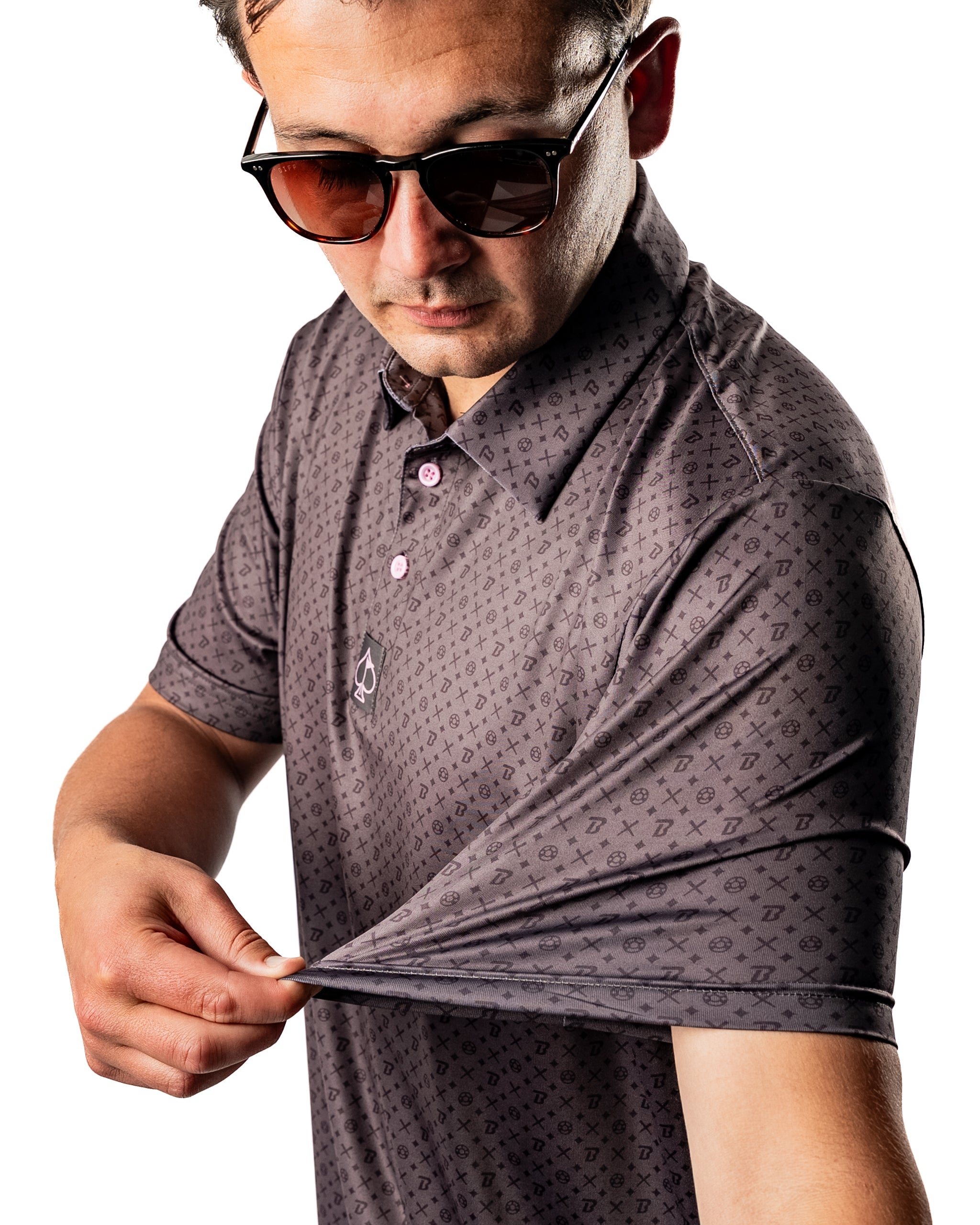 Stylish golfer showcasing a Pins and Aces x Blazy Susan polo shirt with a unique pattern and sunglasses.