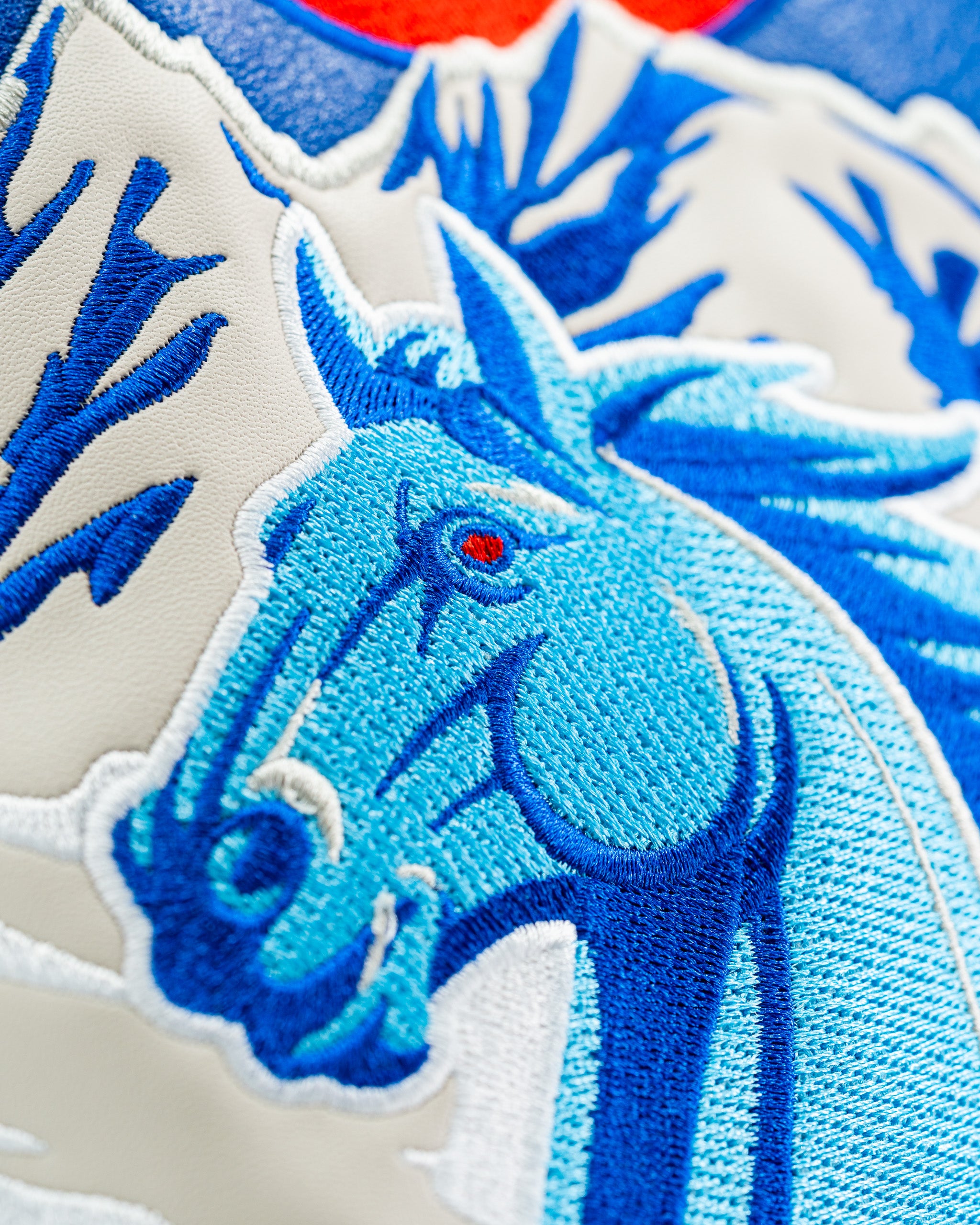 Close-up of a blue embroidered horse head on a driver cover, featuring intricate details and vibrant colors.
