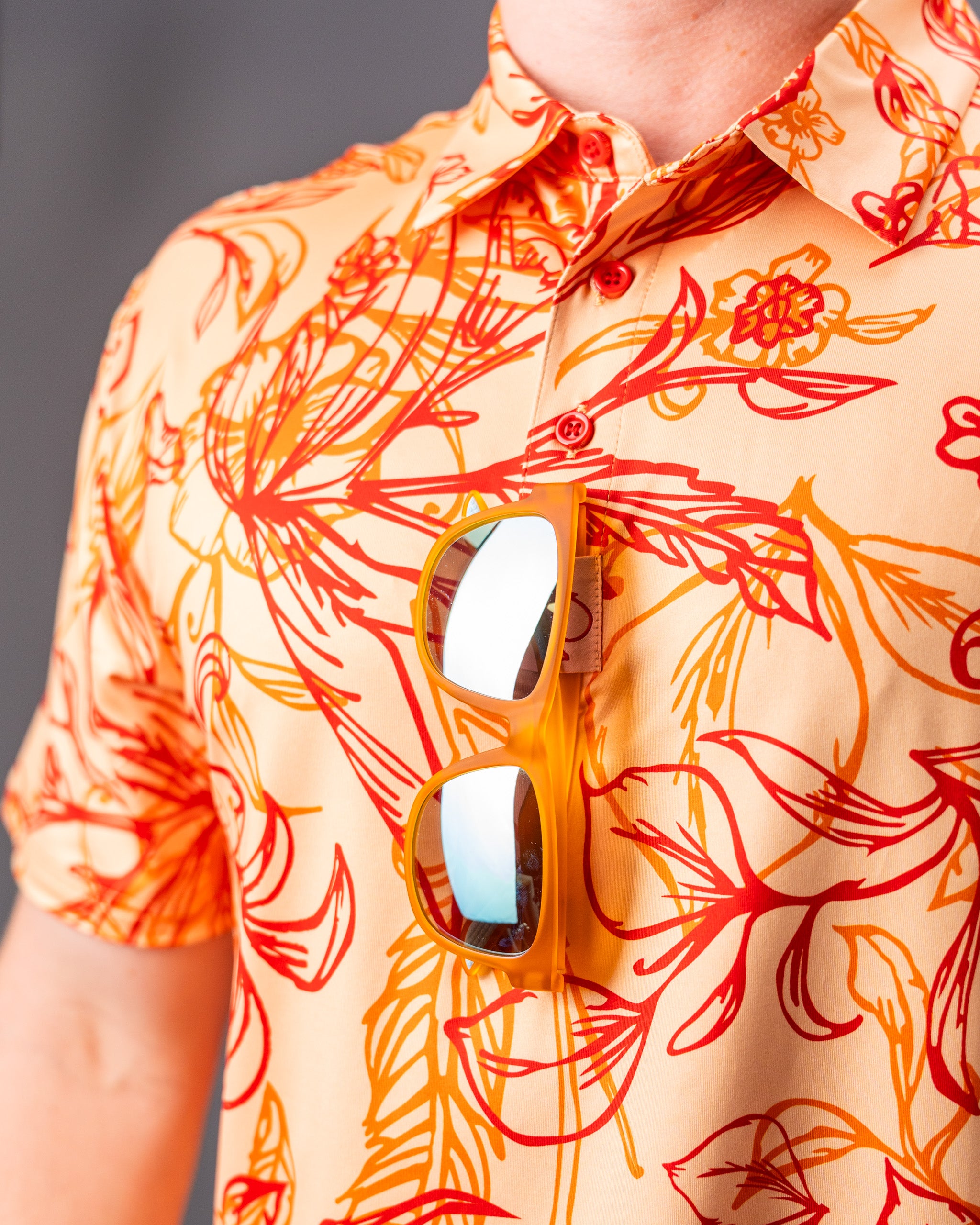 Cabo Sunburst polo shirt in vibrant orange and yellow gradient design, featuring a classic collar and short sleeves.