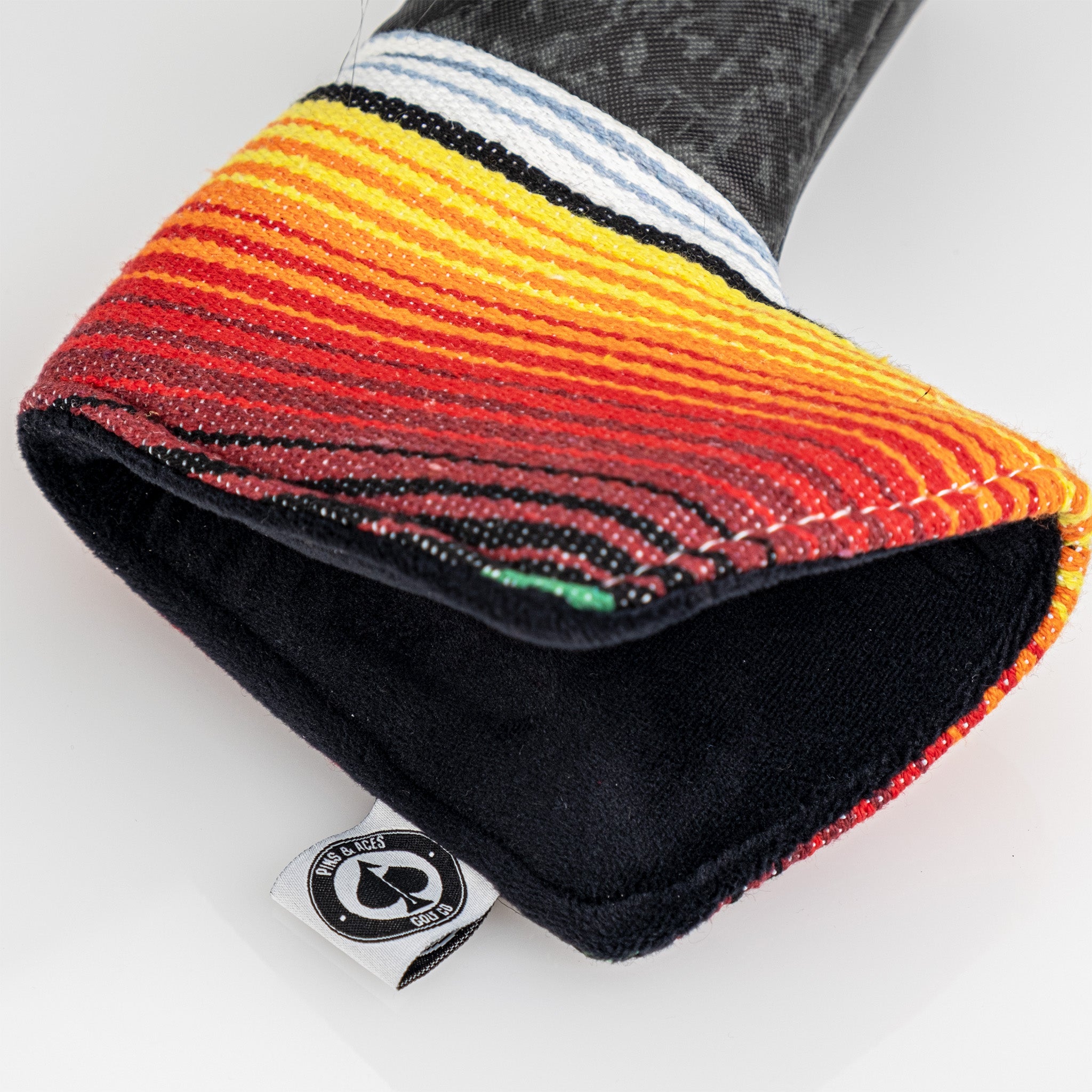 Colorful golf club headcover with bold red, orange, yellow, and black stripes, featuring a textured knit design for golfer...