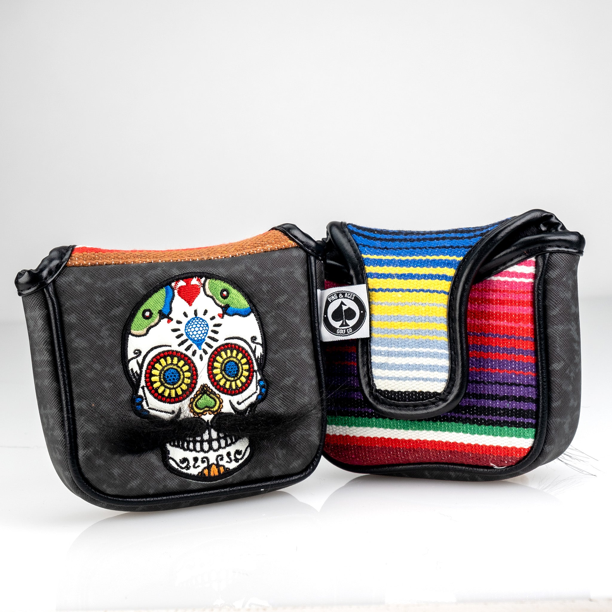 Colorful embroidered skull and striped woven golf headcovers and accessories for bold golfers.