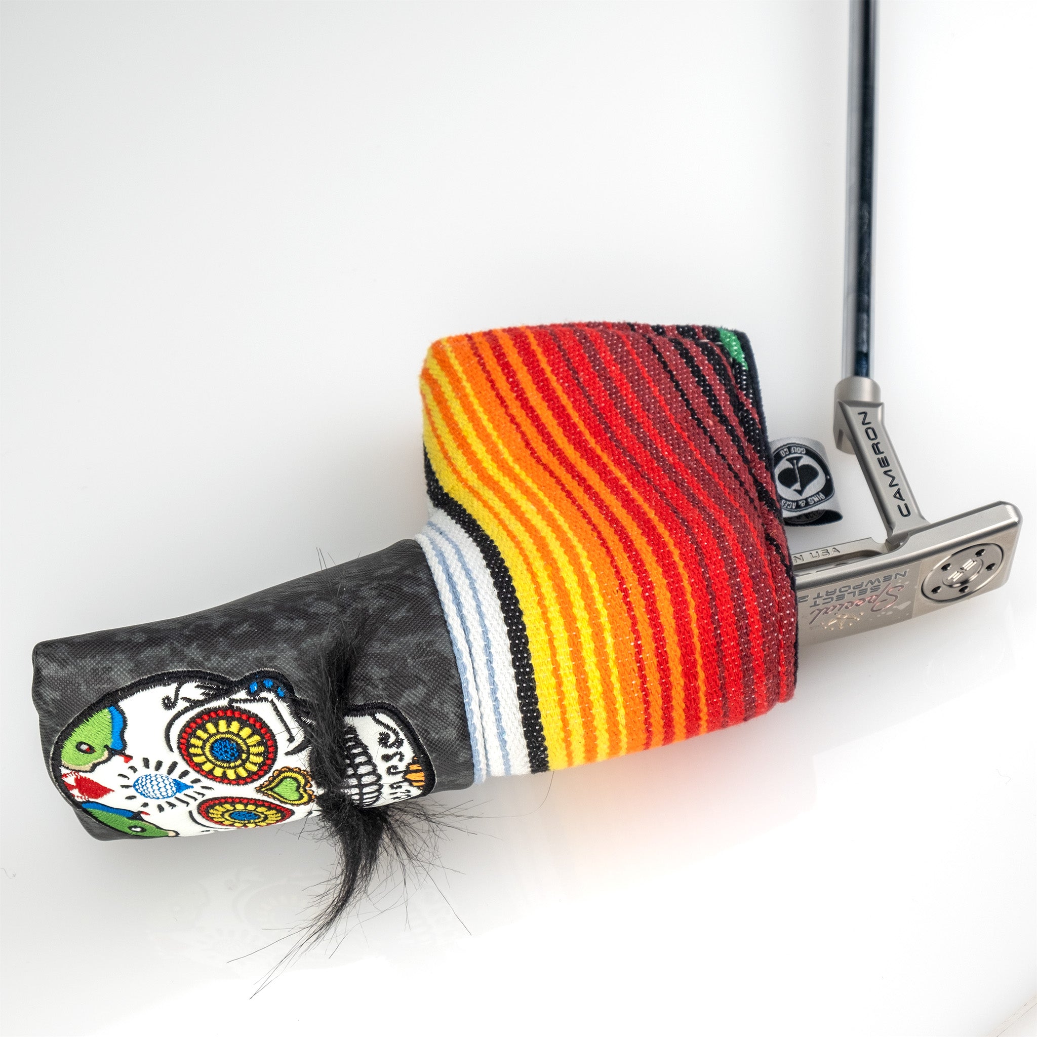 Colorful skull golf club headcover with striped rainbow sock, paired with a silver putter for bold on-course style.