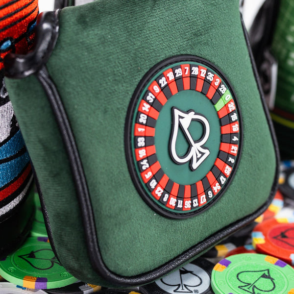 Green golf accessory bag featuring a logo with a playing card spade and roulette wheel design, perfect for bold golf style.