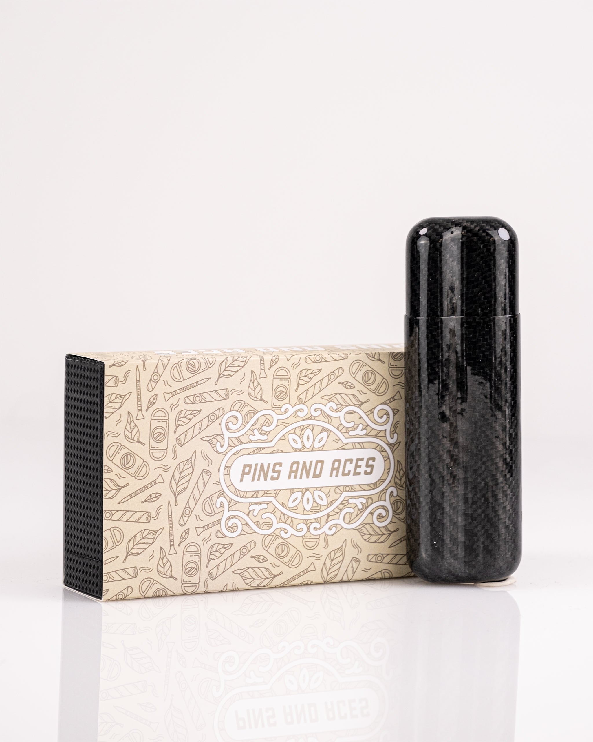 Black carbon fiber golf headcover with a sleek, glossy finish, paired with a beige Pins and Aces branded box featuring pla...