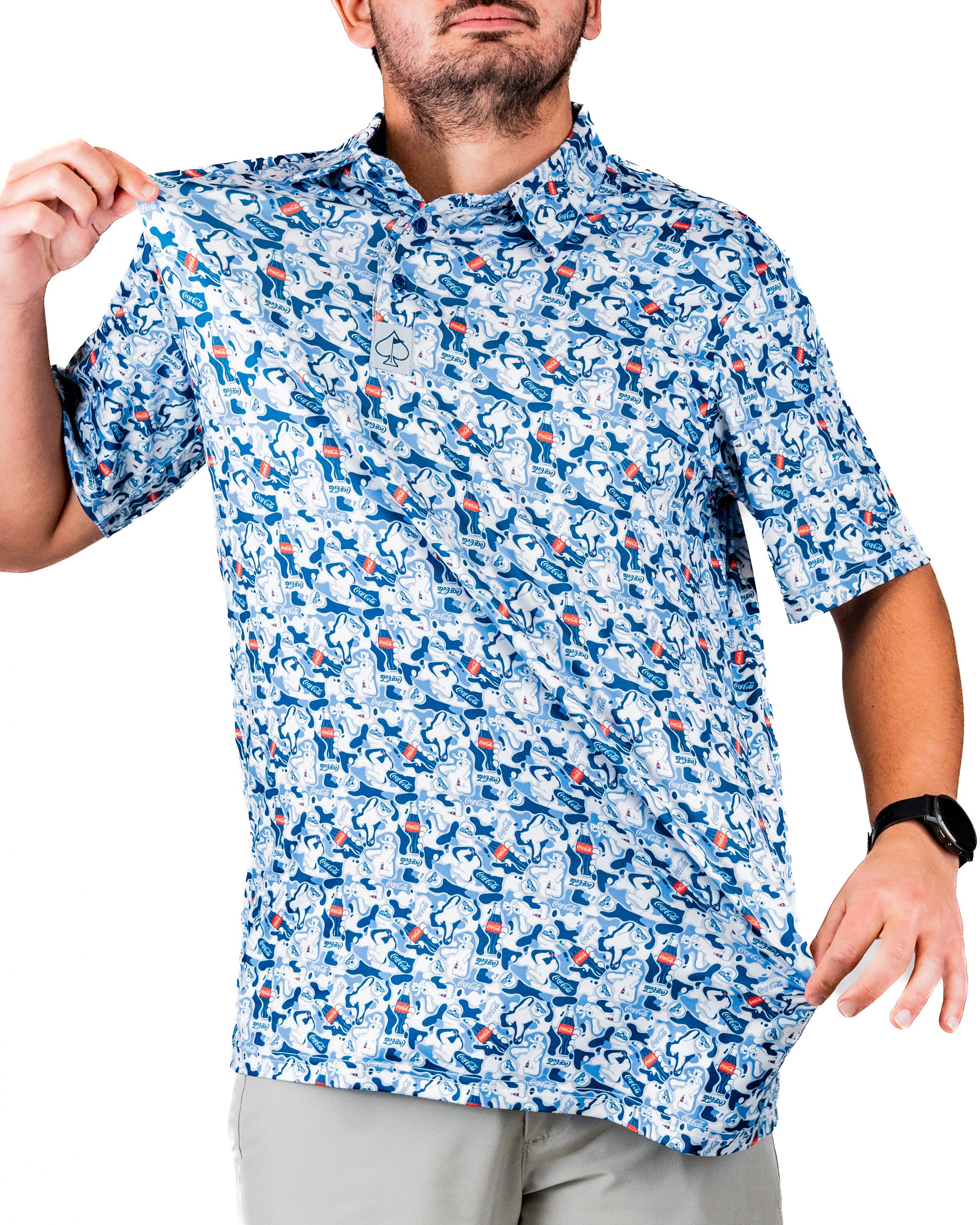 A man wearing a short-sleeve, blue patterned golf shirt featuring Coca-Cola-themed designs, showcasing the fabric.
