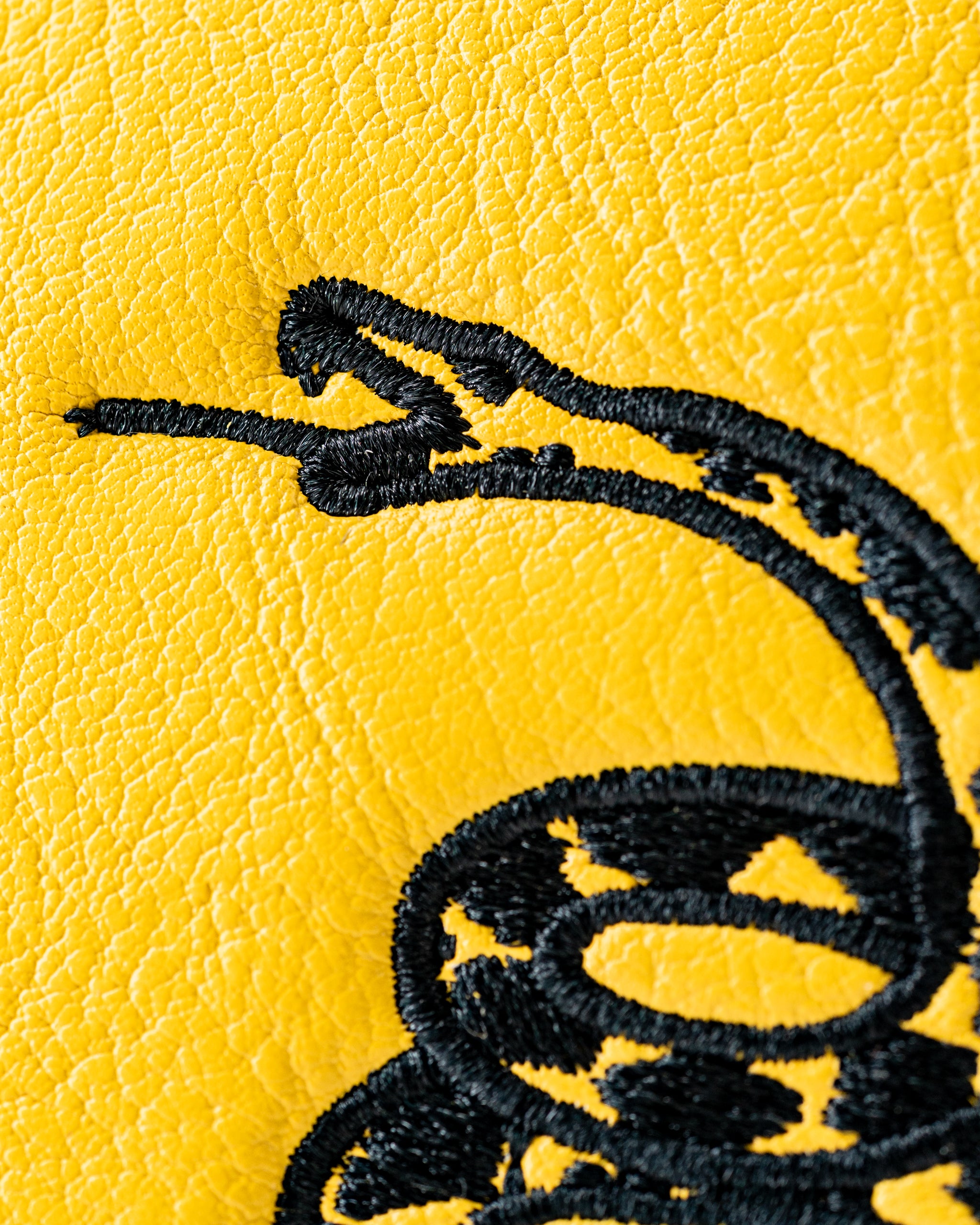 Close-up of a yellow mallet putter cover featuring a black embroidered snake design, symbolizing "Don't Tread on Me.