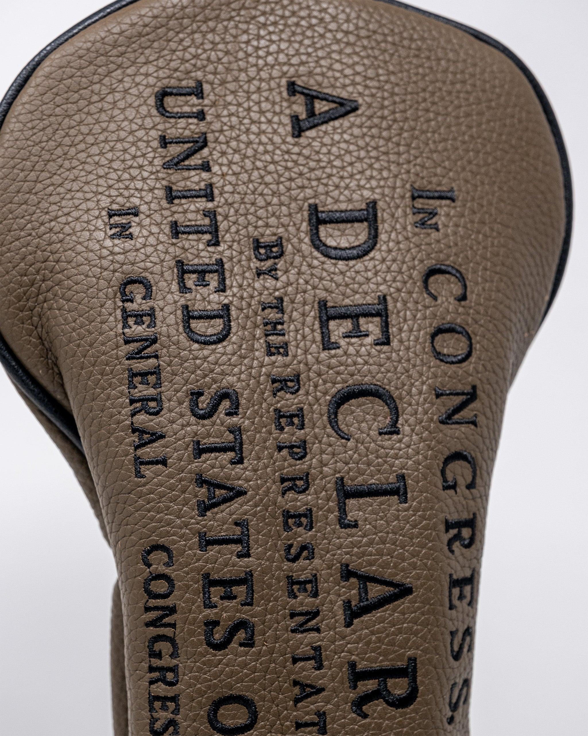 Close-up of a brown driver golf club headcover with black embroidered text reading Declaration Driver, emphasizing texture and design.