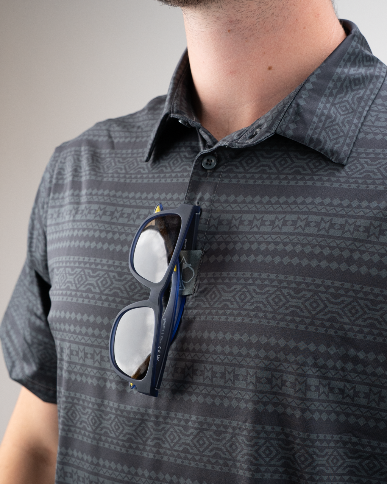 Men's Desert Geo golf shirt featuring a geometric pattern, with sunglasses resting on the collar for a stylish look.