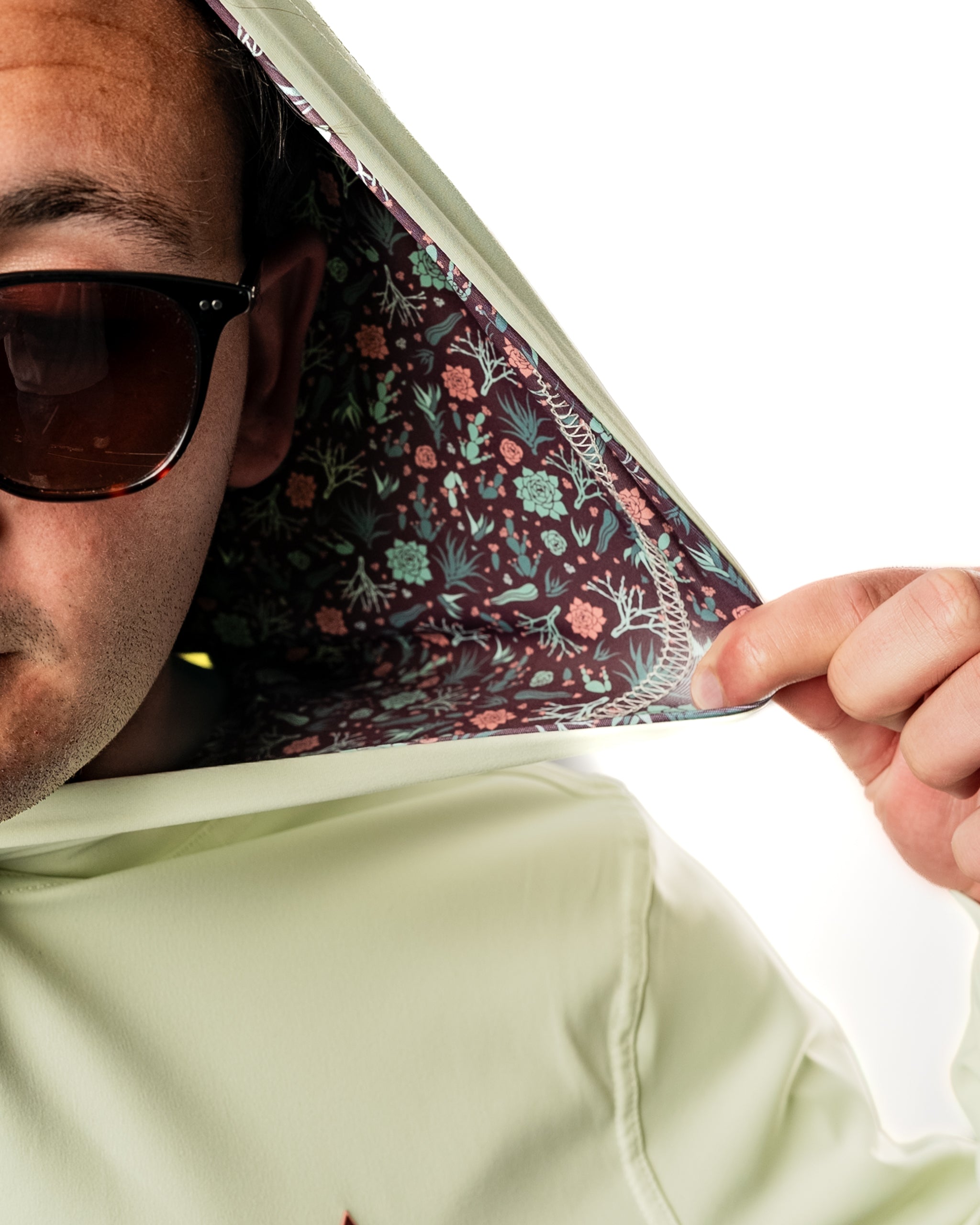 Performance Golf Hoodie in Desert Sage featuring a floral-patterned interior and a model wearing sunglasses.