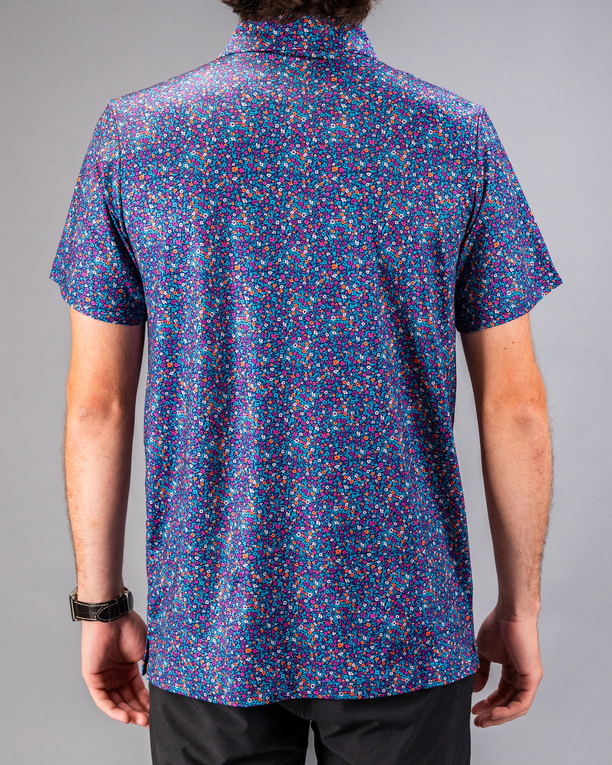 Men's short-sleeve golf shirt featuring a vibrant lavender floral pattern on a dark background, ideal for stylish play.