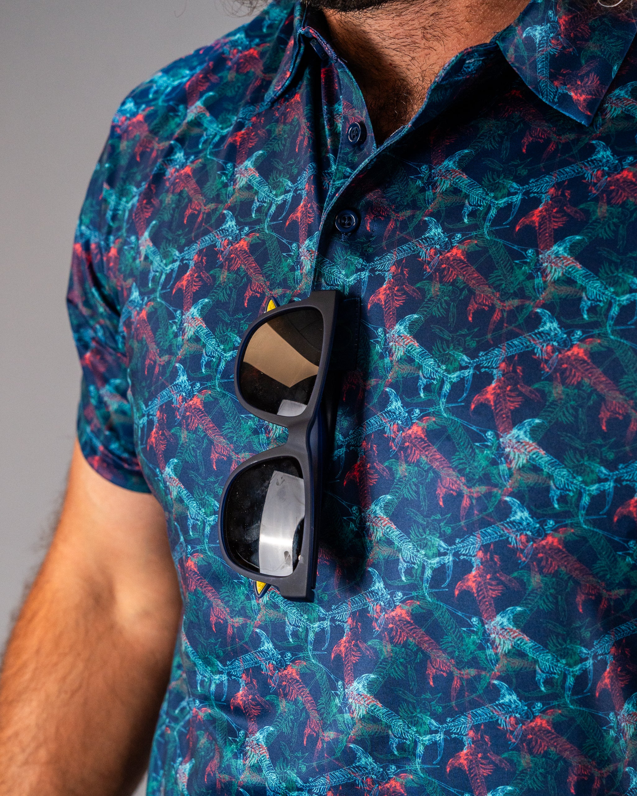 Bold golf shirt featuring a vibrant swordfish and skeleton pattern, paired with stylish sunglasses on the chest.