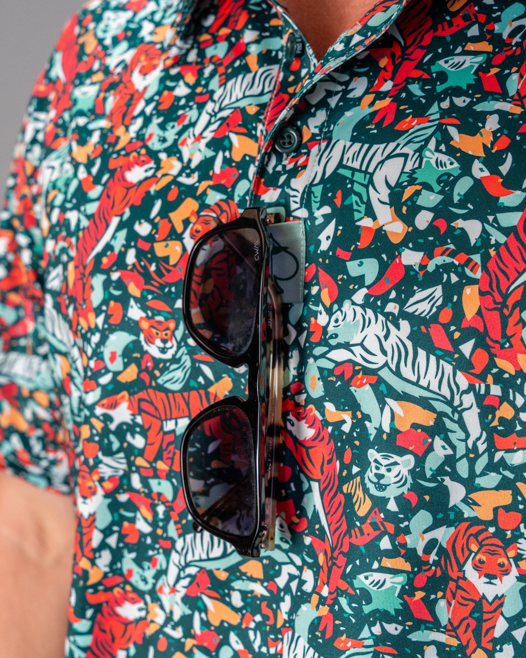Bold teal golf shirt featuring a vibrant tiger print, paired with stylish sunglasses for a standout look on the course.