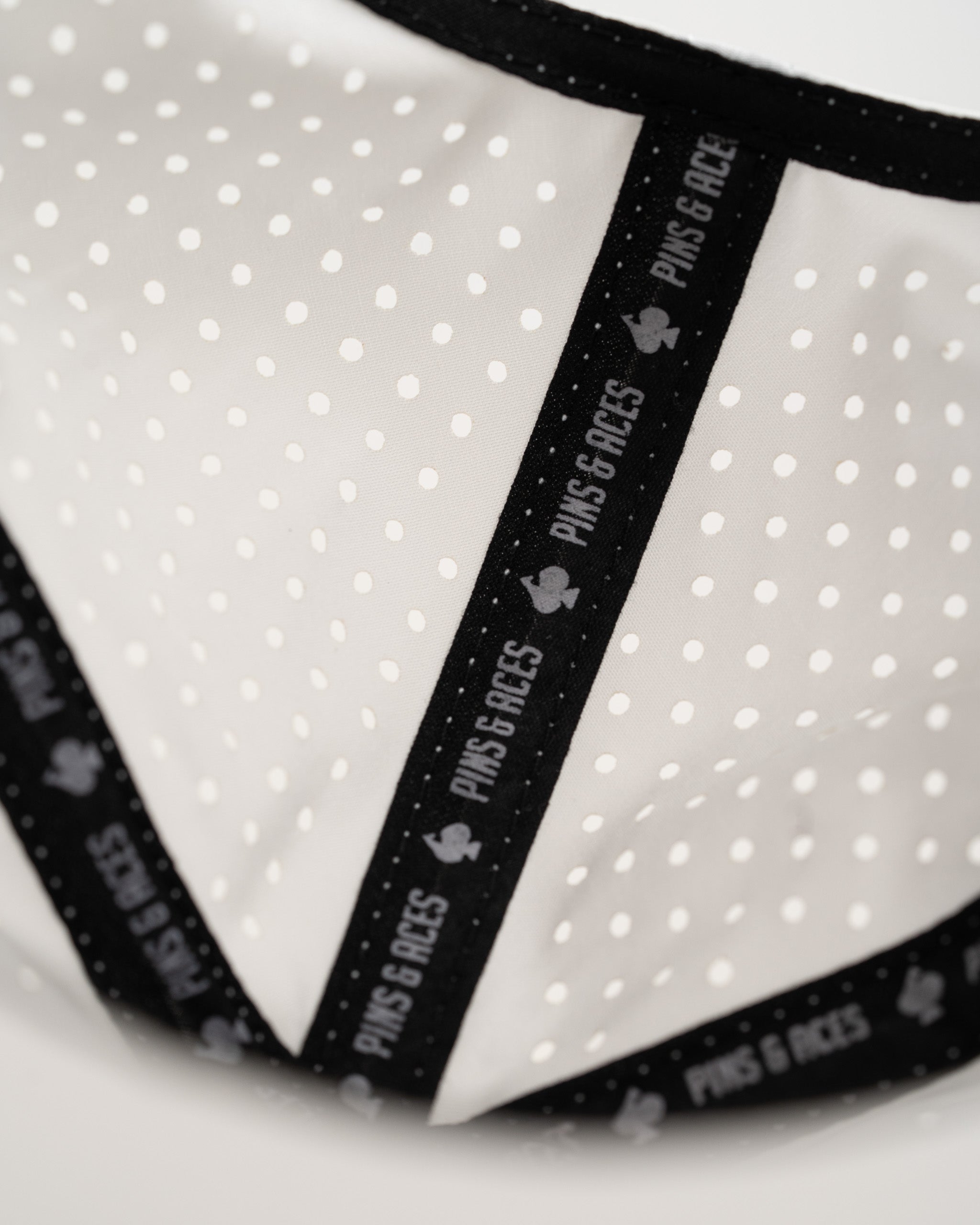 Perforated white hat featuring black branding and a unique rope design, perfect for bold golfers.