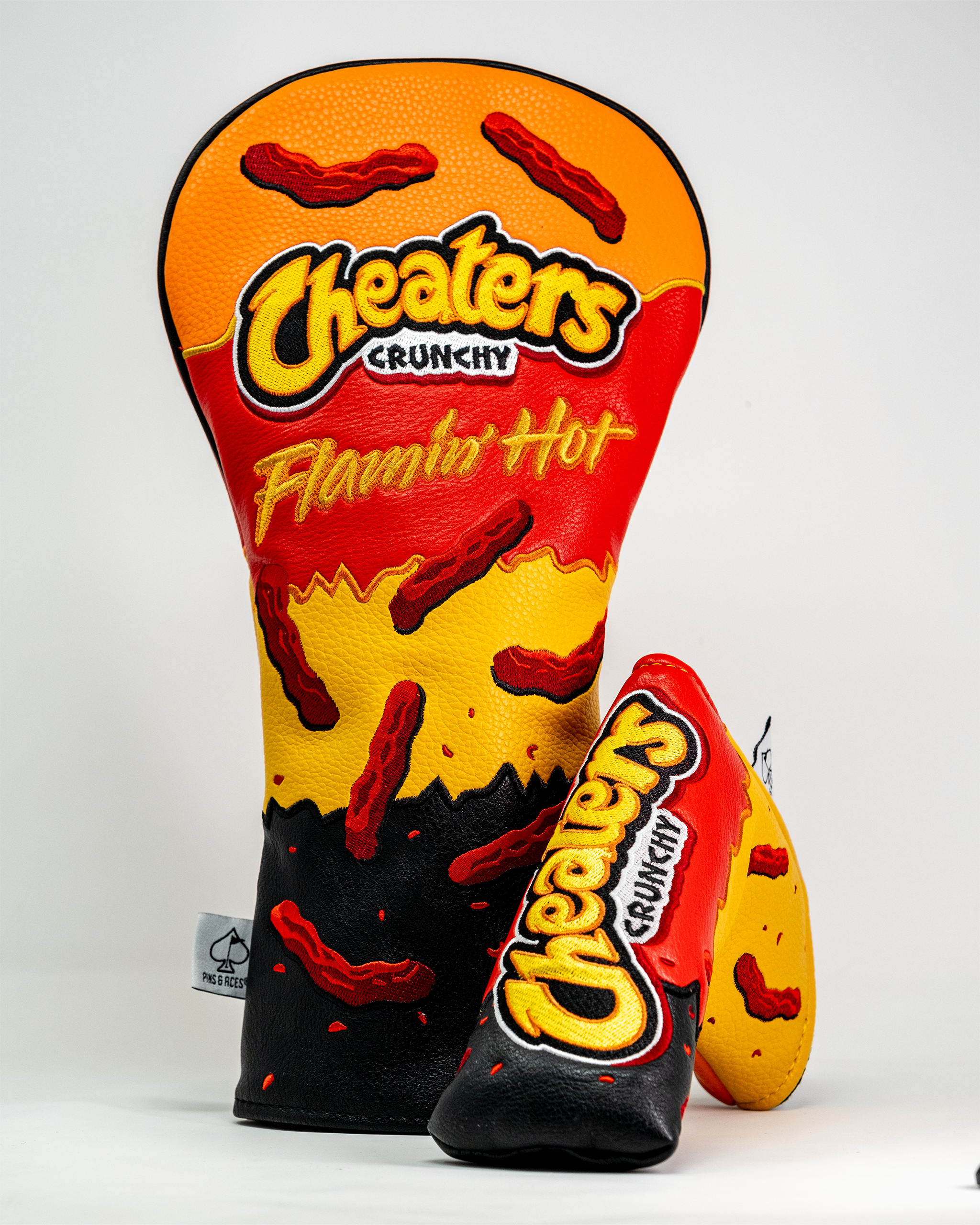 Golf club blade cover featuring a Cheaters Flamin' Hot Crunchy snack design with red, yellow, and black colors and chili pepper graphics.