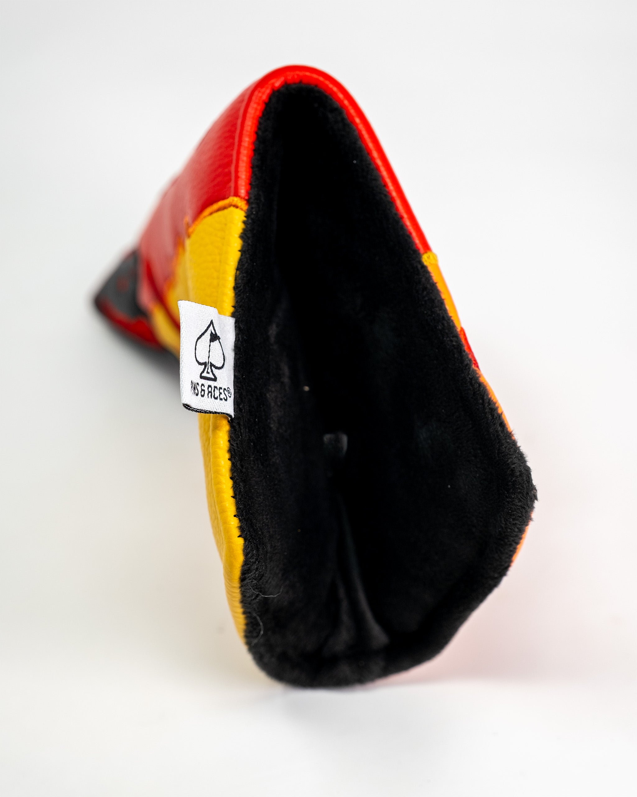 Close-up of a Flamin' Hot Cheaters Blade Putter Cover with red, yellow, and black colors, showing the interior and a fabric tag.
